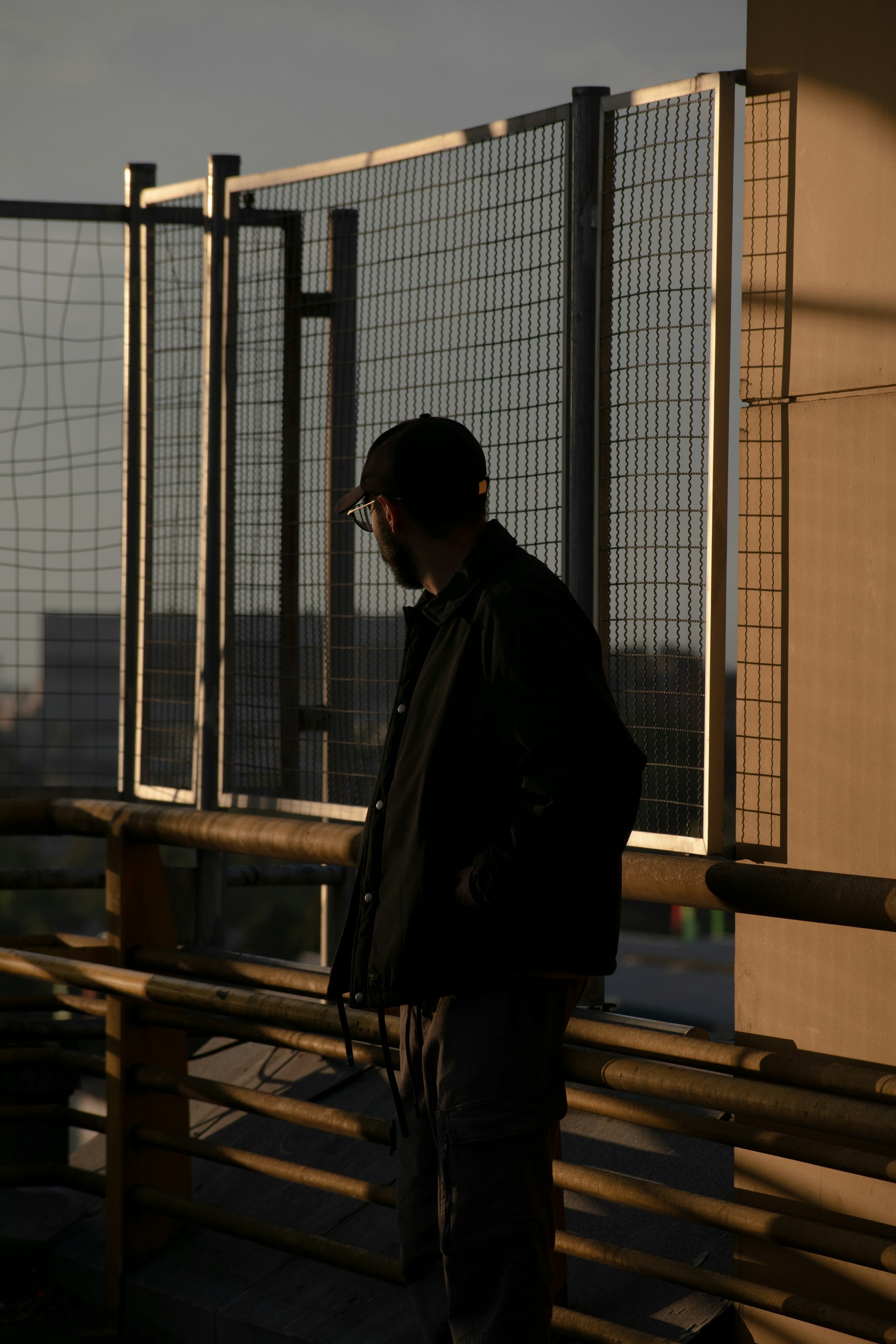 A man standing on top of a building next to a fence