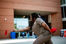 A woman is throwing a frisbee in front of a building