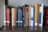 A bookshelf filled with lots of books on top of a wooden table