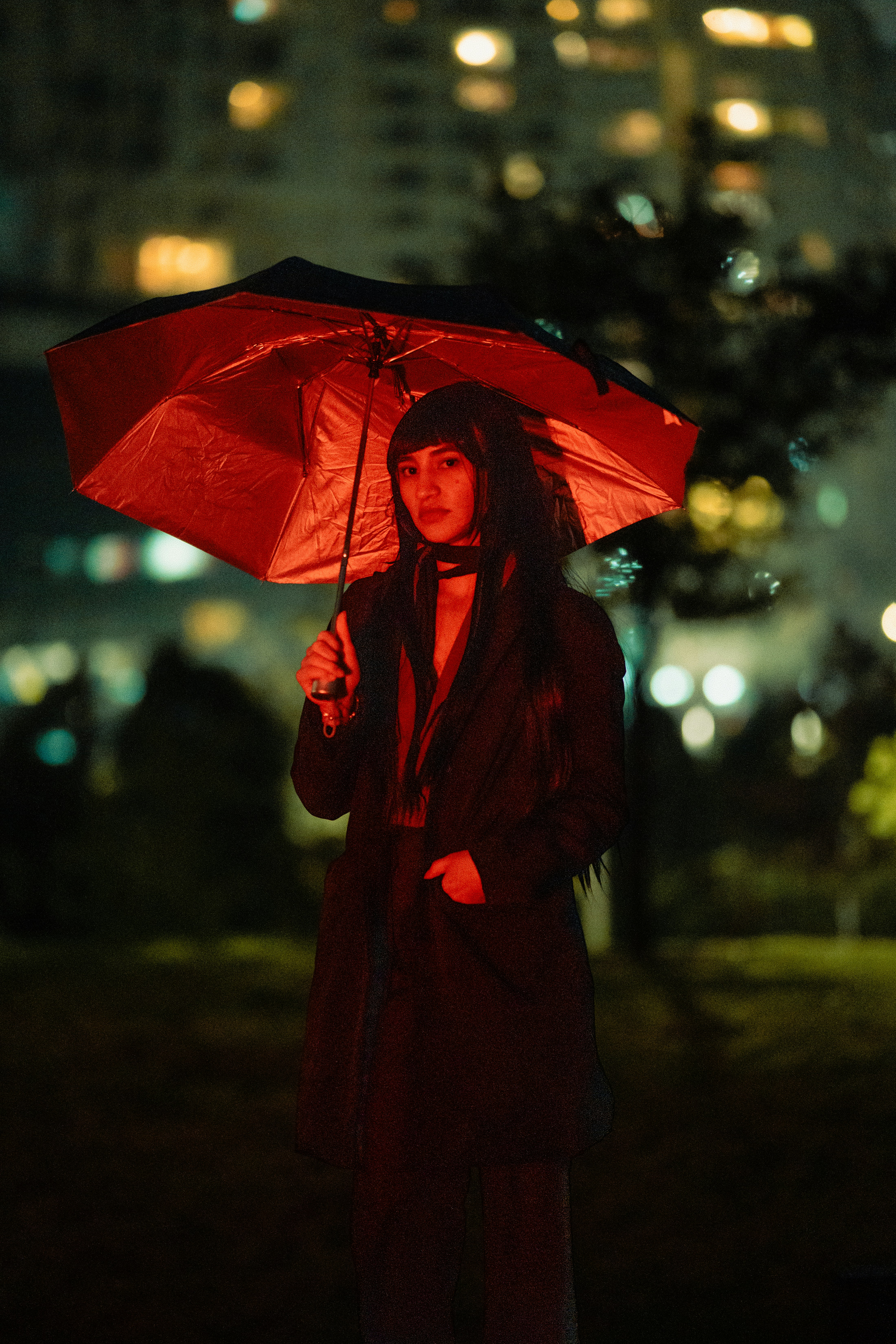 A woman in a red coat holding a red umbrella