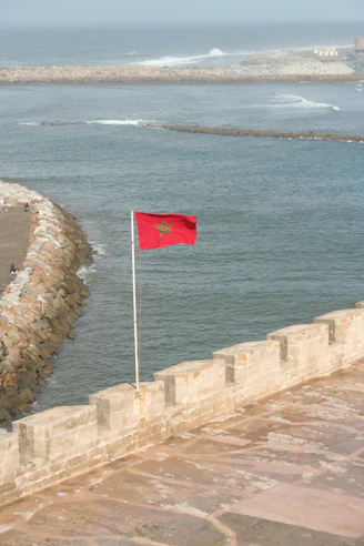 A red flag on a stone wall by the water