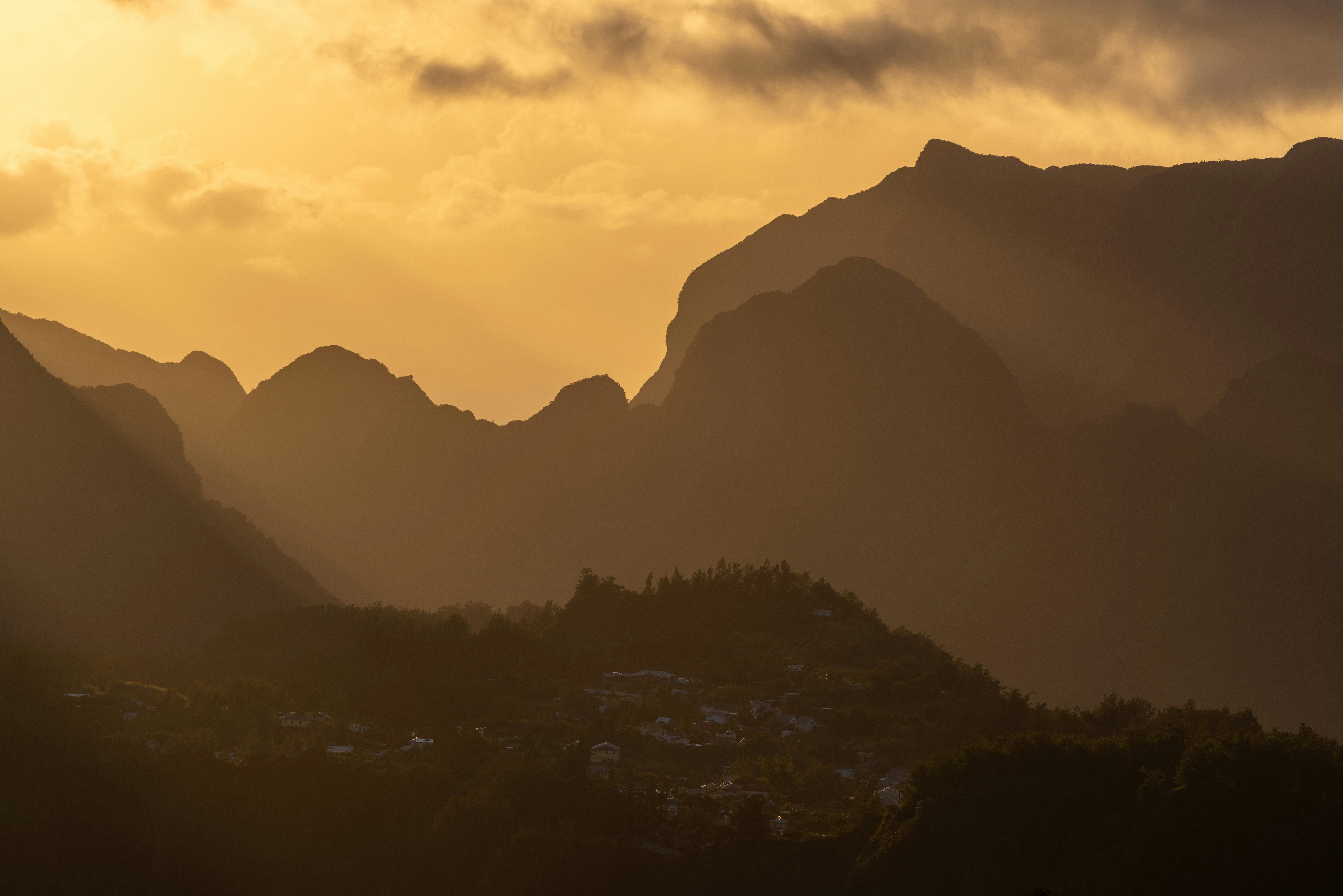 The sun is shining through the clouds over the mountains