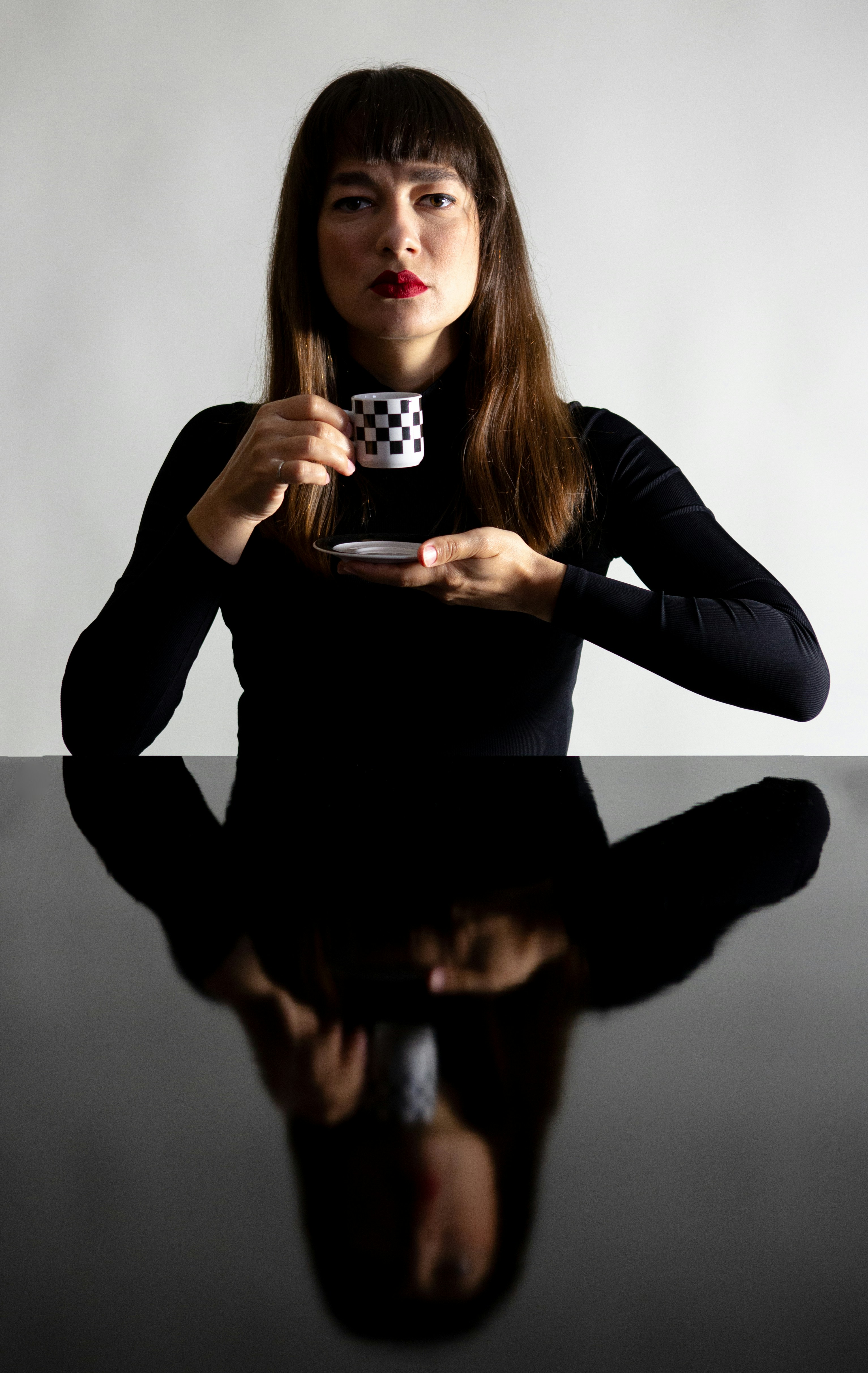 A woman sitting at a table holding a cup of coffee
