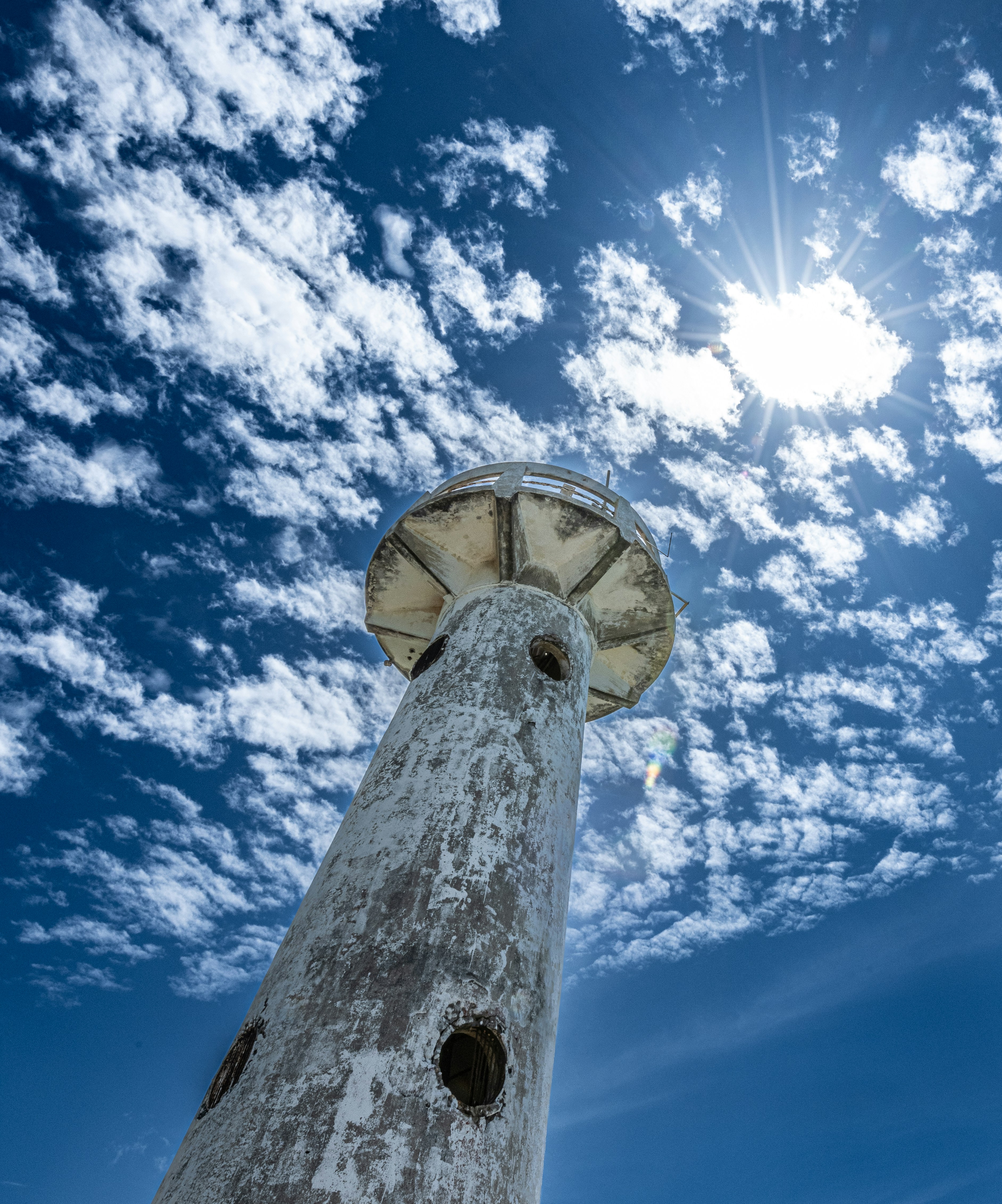 Ein hoher weißer Turm unter blauem Himmel mit Wolken