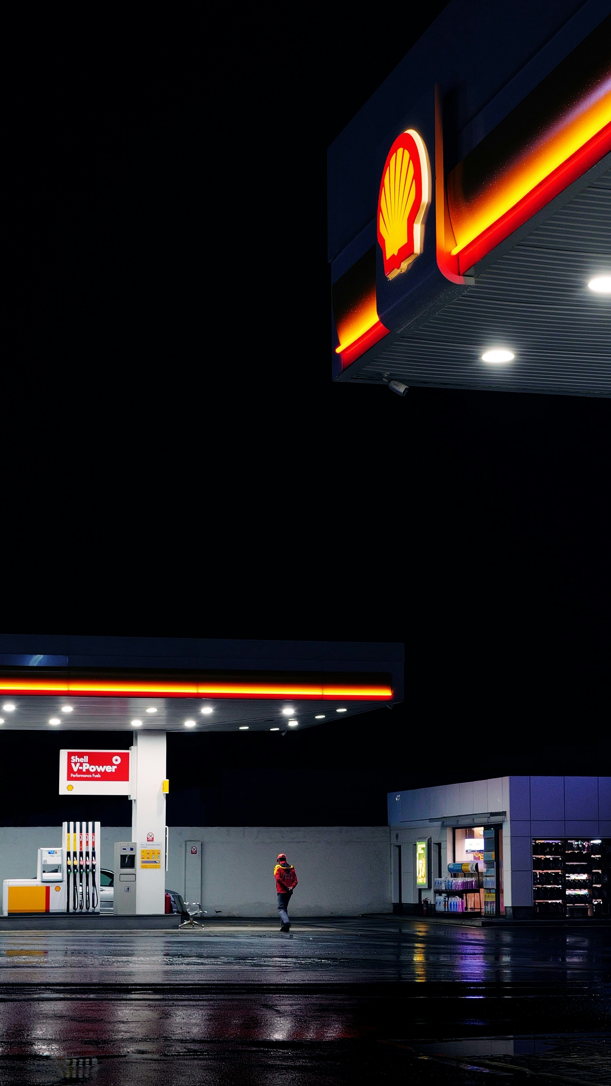 Une station-service la nuit avec une personne qui passe