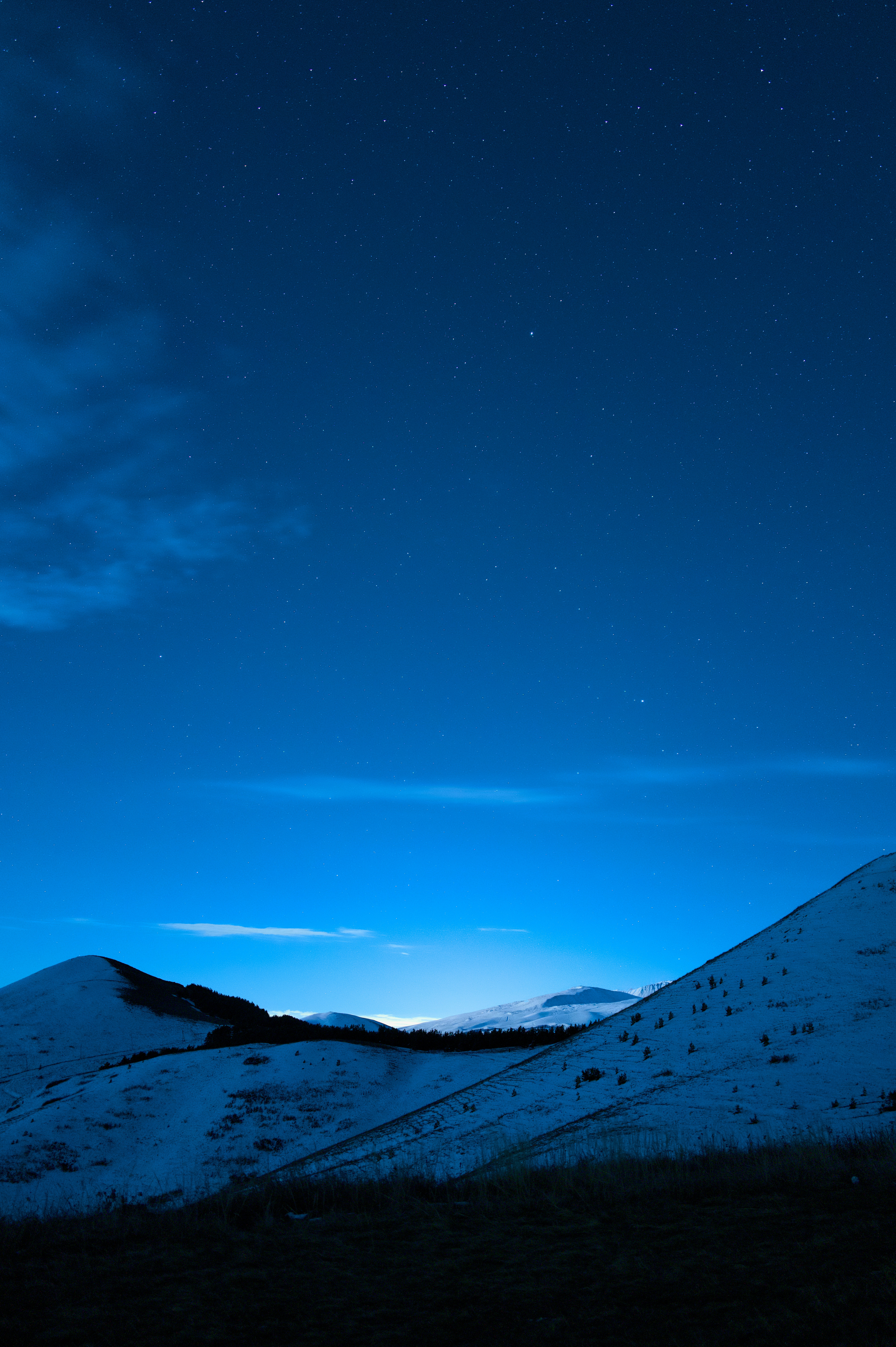 A hill covered in snow under a night sky