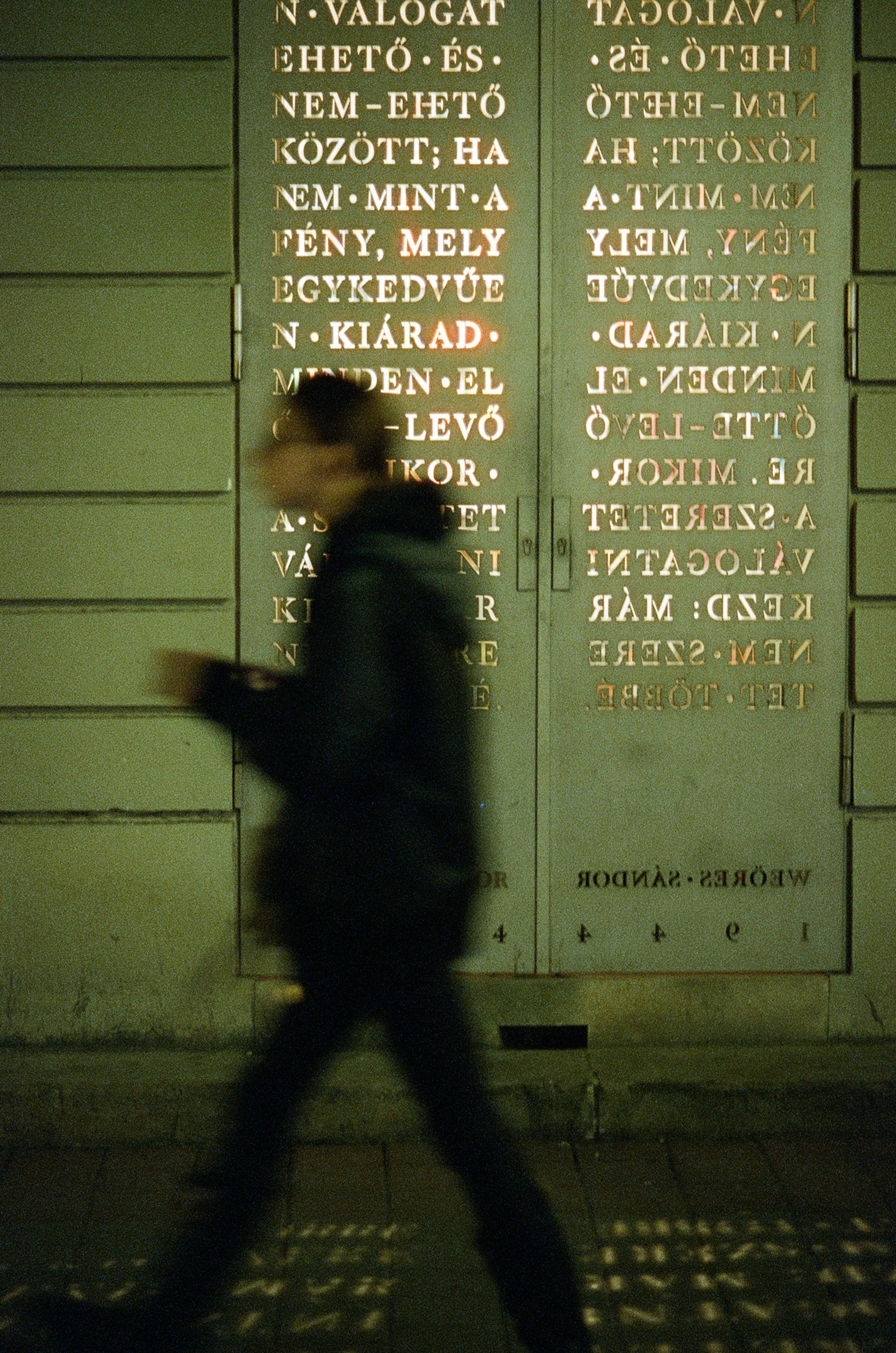 A man walking past a wall with writing on it