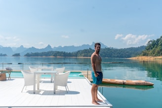 A man standing on a dock next to a table and chairs