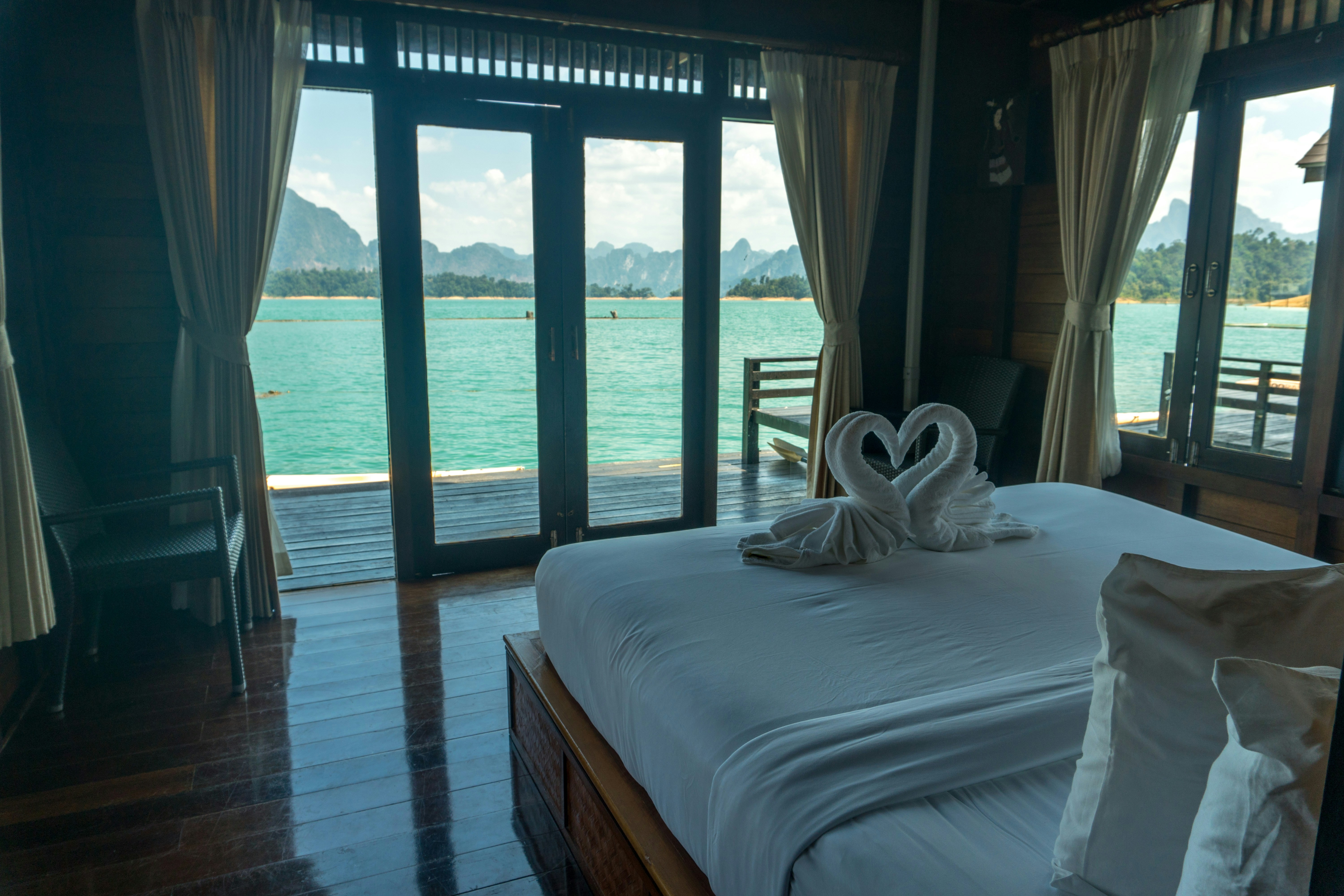 A room with a bed and a balcony with a view of the water