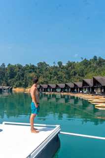A man standing on a dock next to a body of water