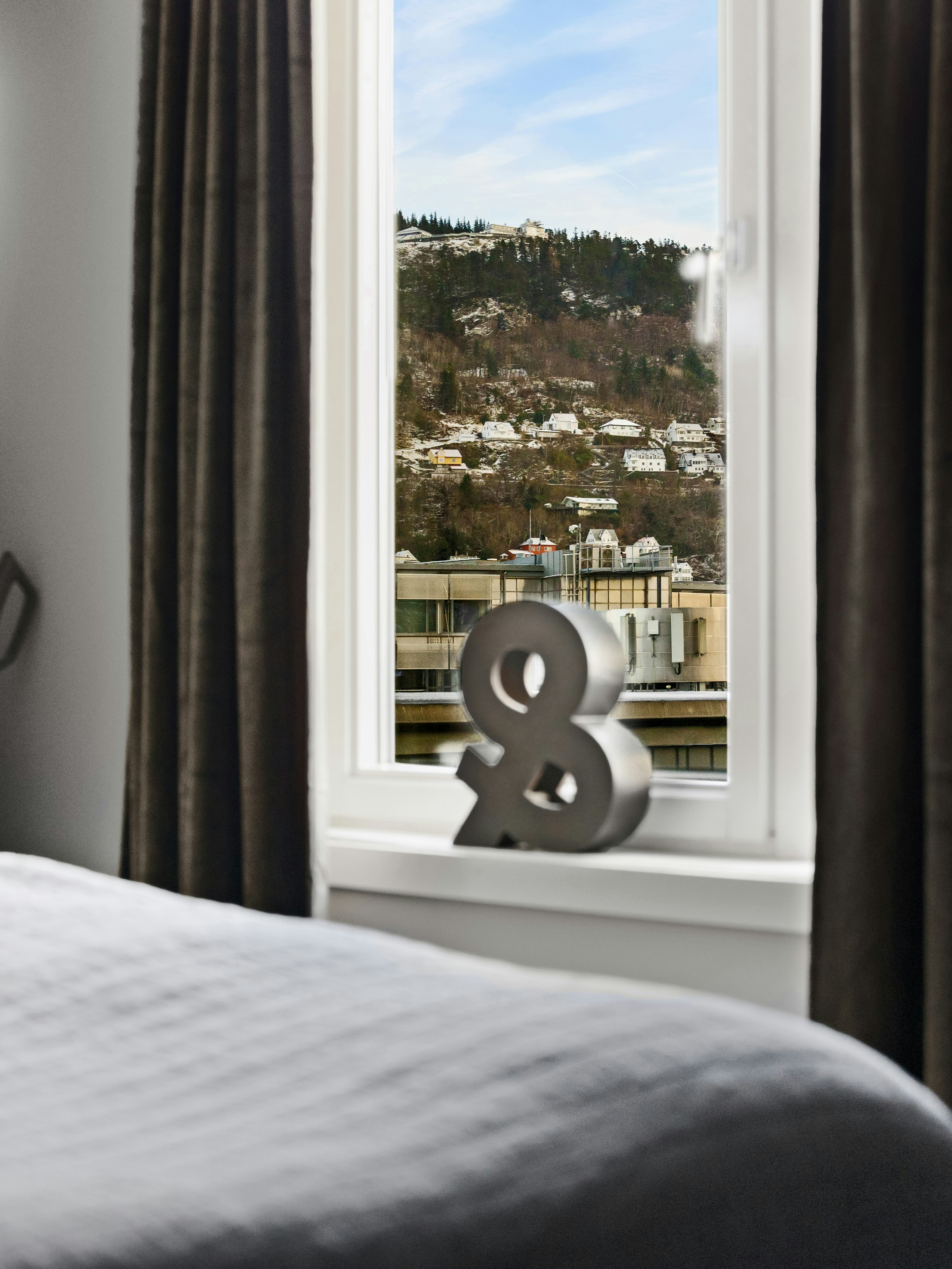 Ein Bett neben einem Fenster mit Blick auf eine Stadt