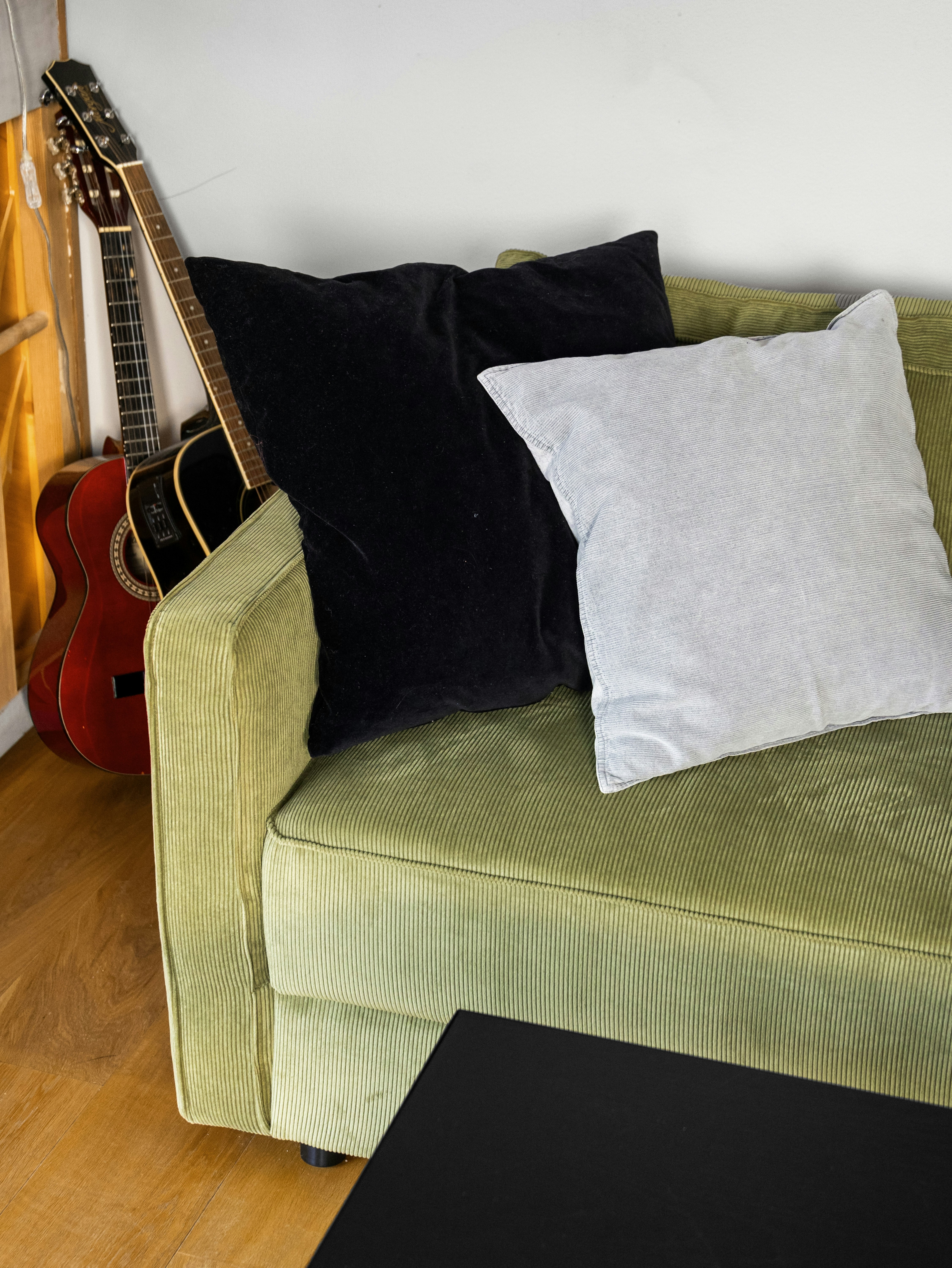 Ein Wohnzimmer mit einer grünen Couch und einer Gitarre