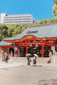 A group of people with umbrellas standing in front of a building