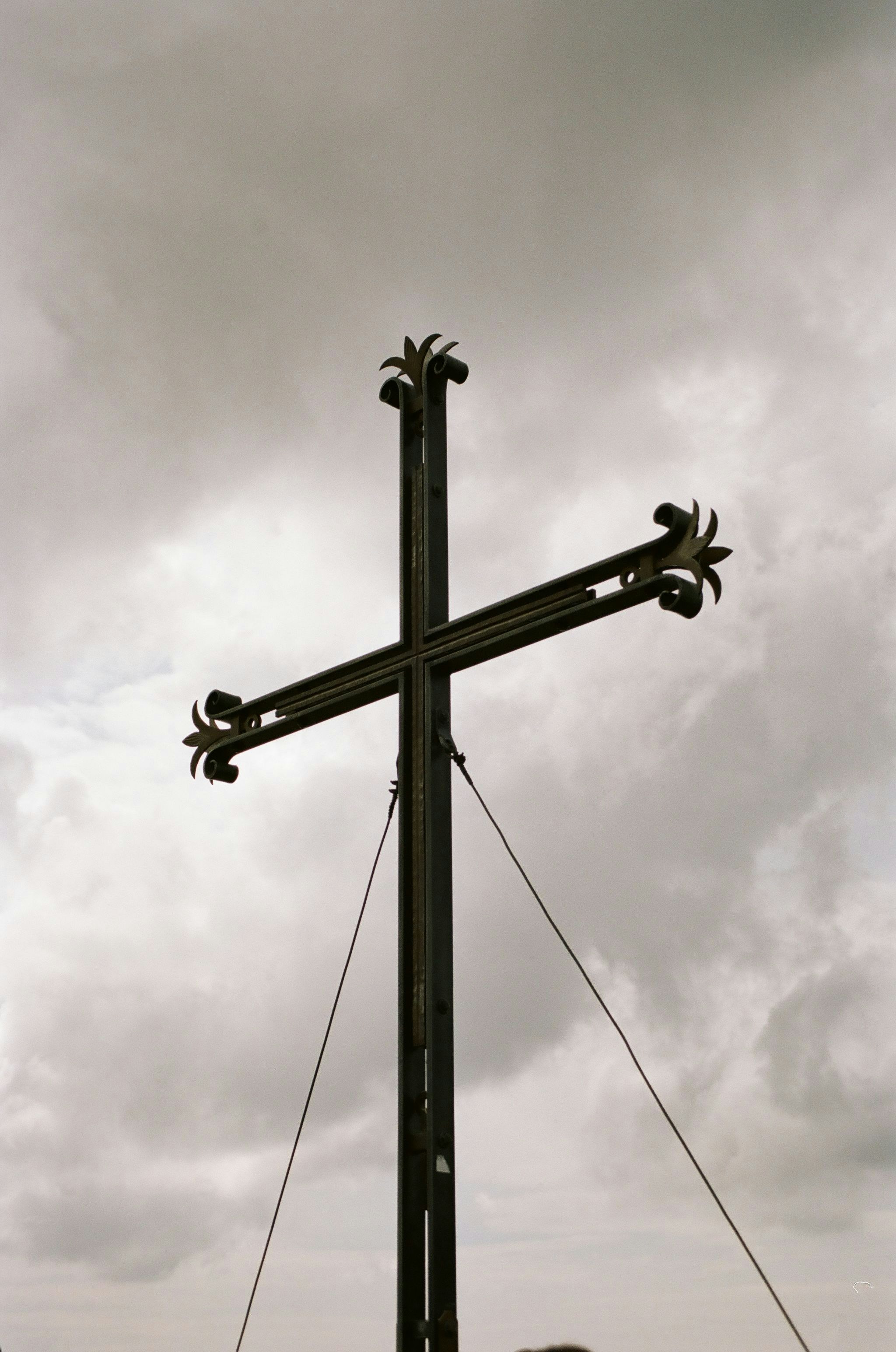 A man standing next to a cross on top of a hill