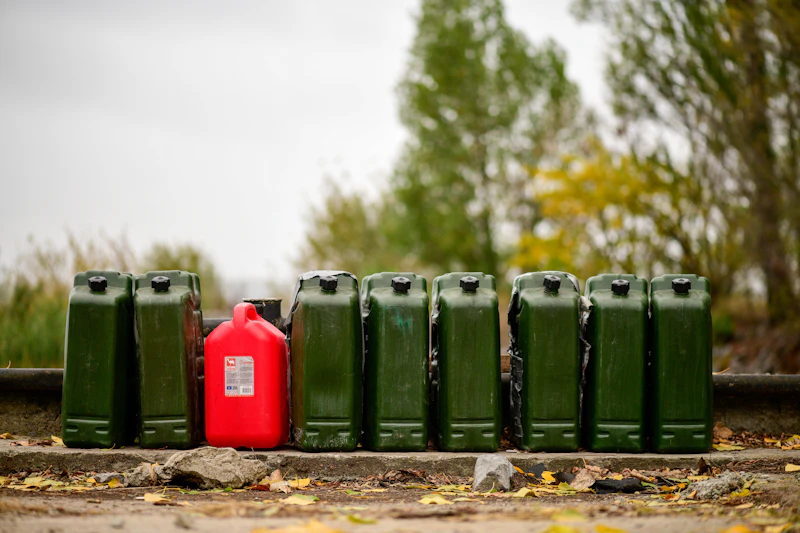 Row of coloured fuel jerrycans — green, red, white and purple plastic fuel canisters