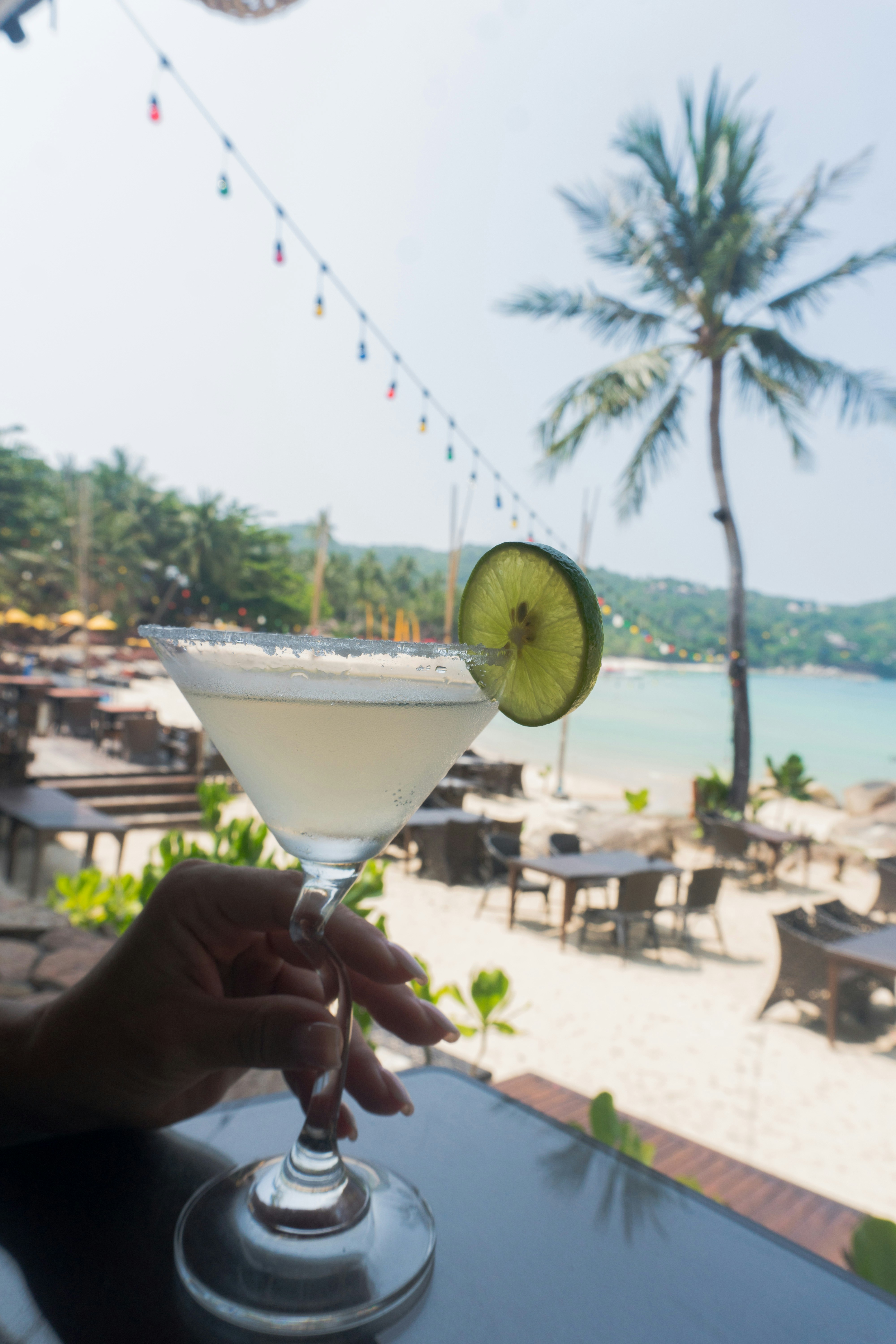 A person holding a drink in front of a beach