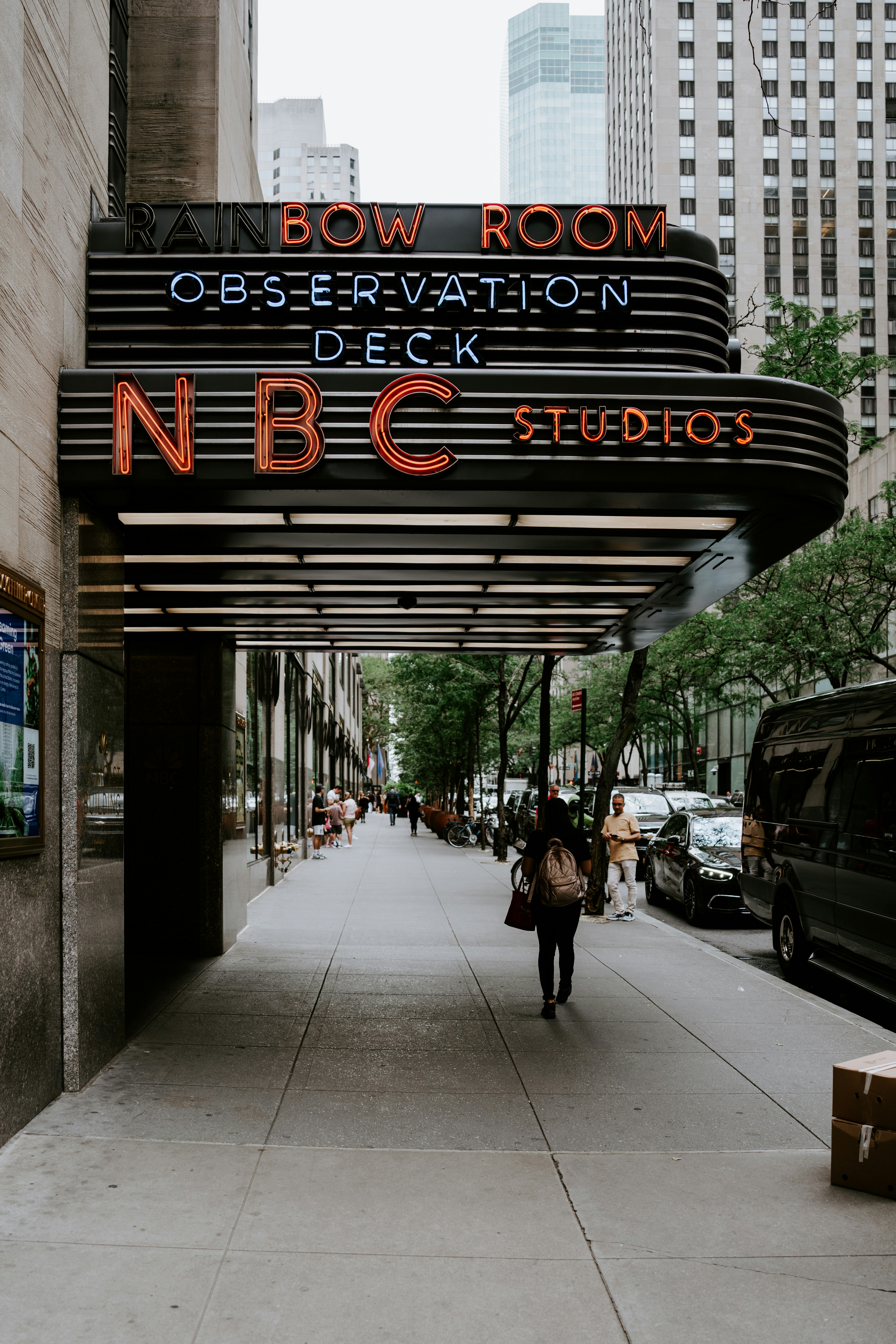 A person walking down a sidewalk under a sign