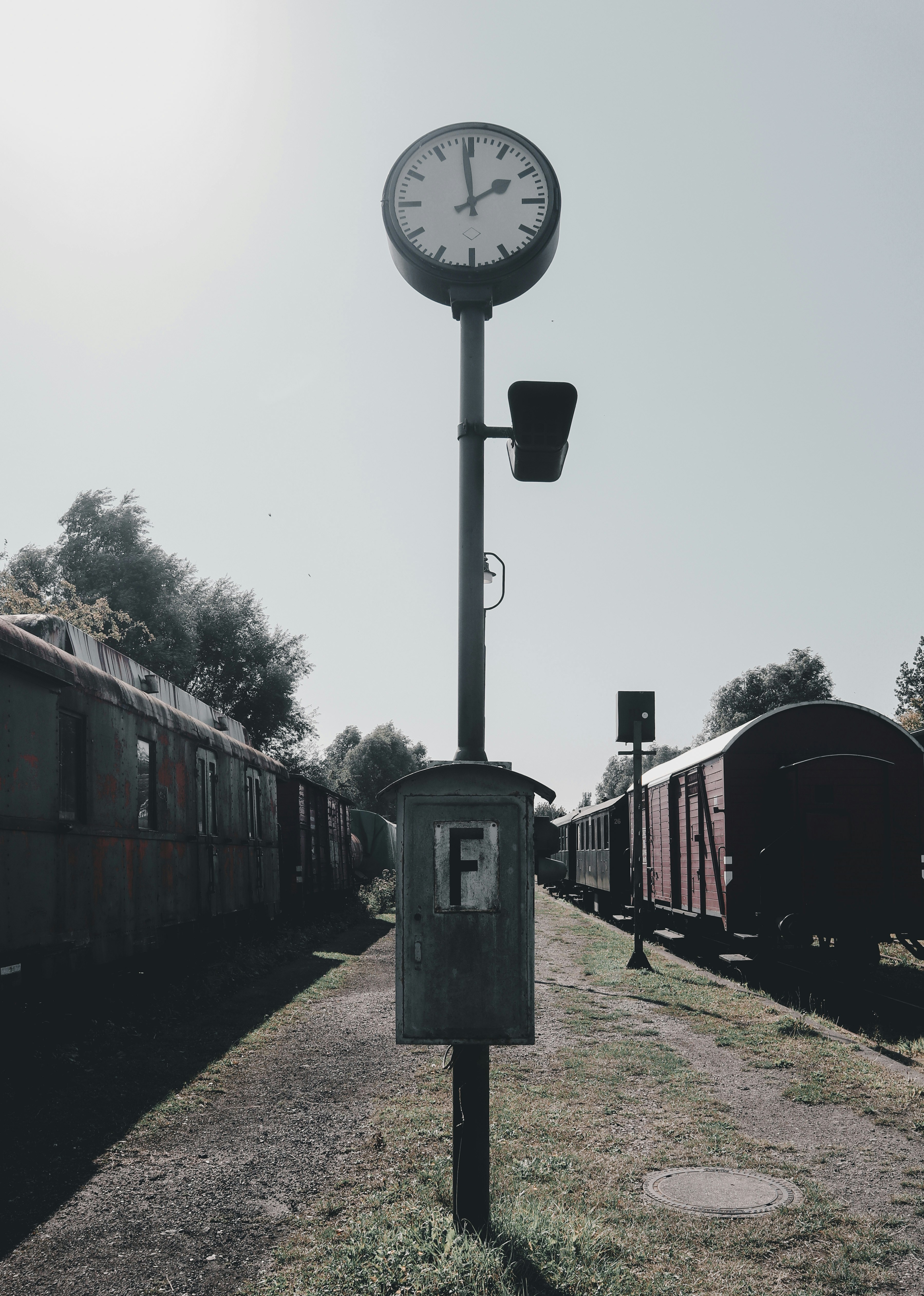 A clock on a pole next to a train