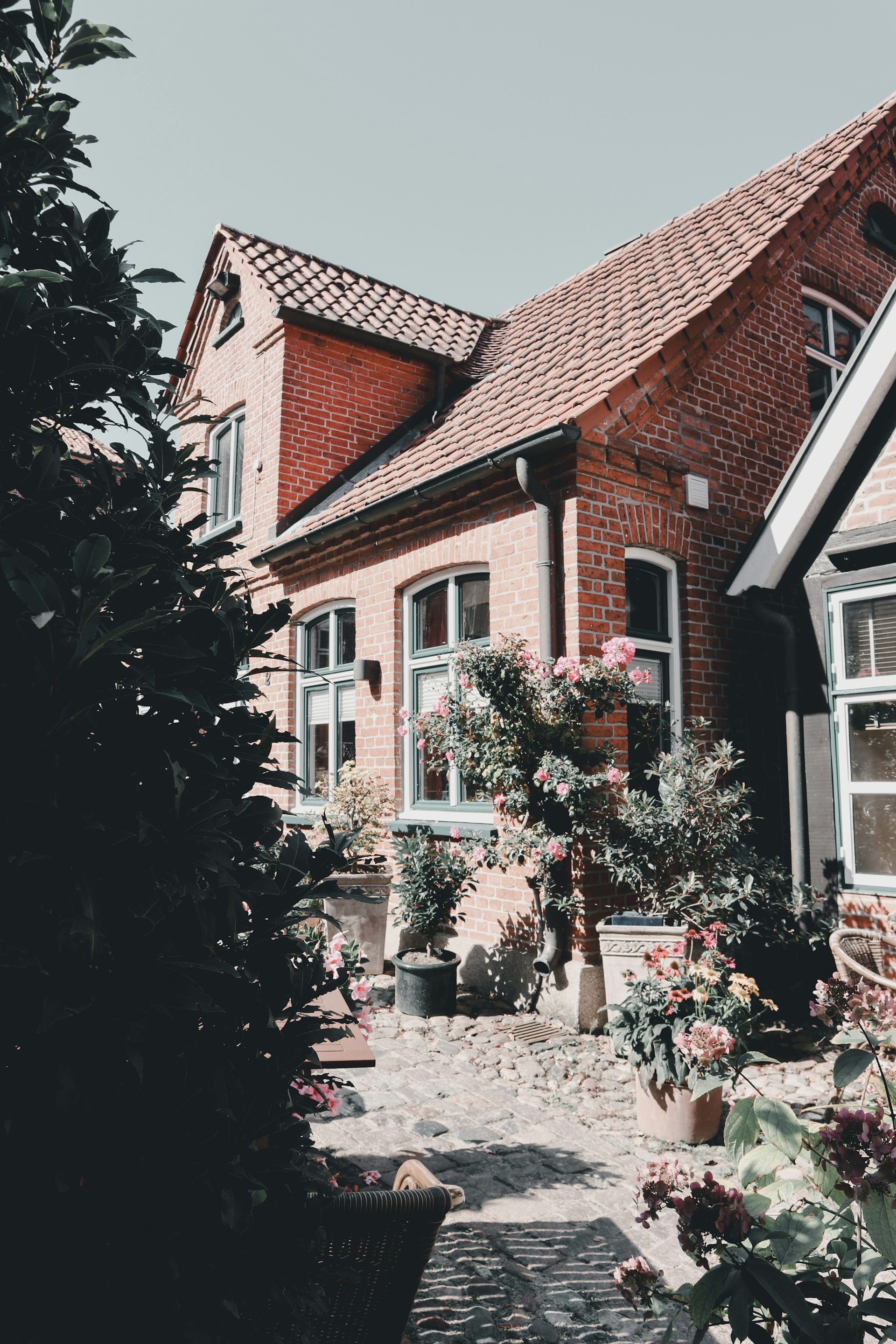 A brick house with lots of windows and flowers