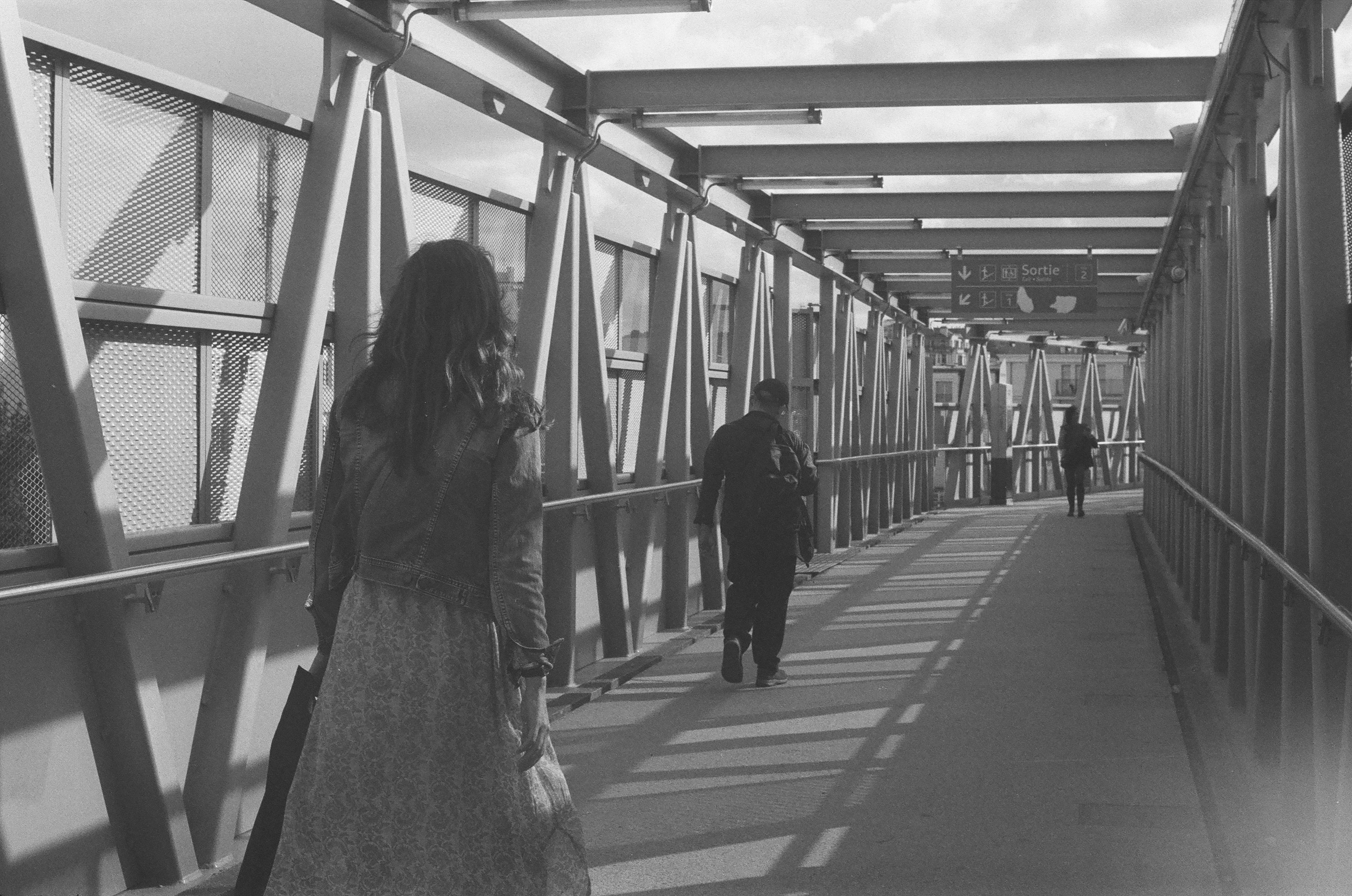 A black and white photo of people walking on a bridge