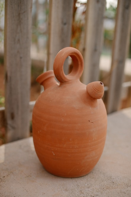 A brown vase sitting on top of a cement slab