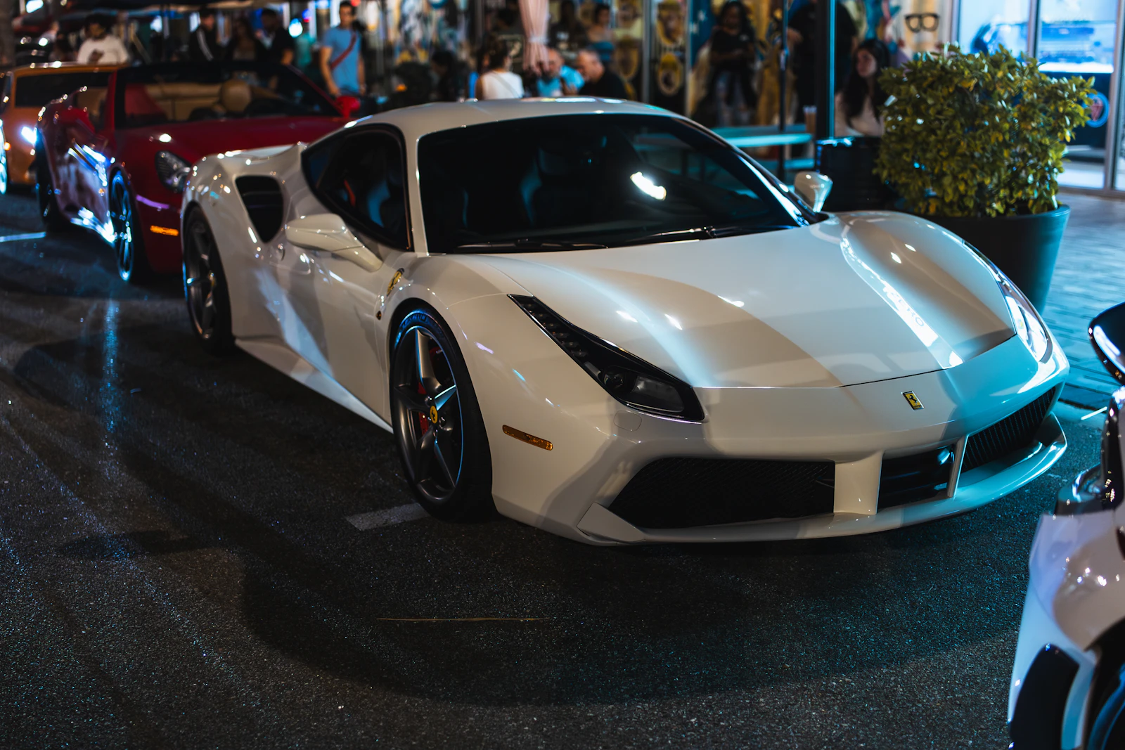 White Ferrari parked on a busy street at night