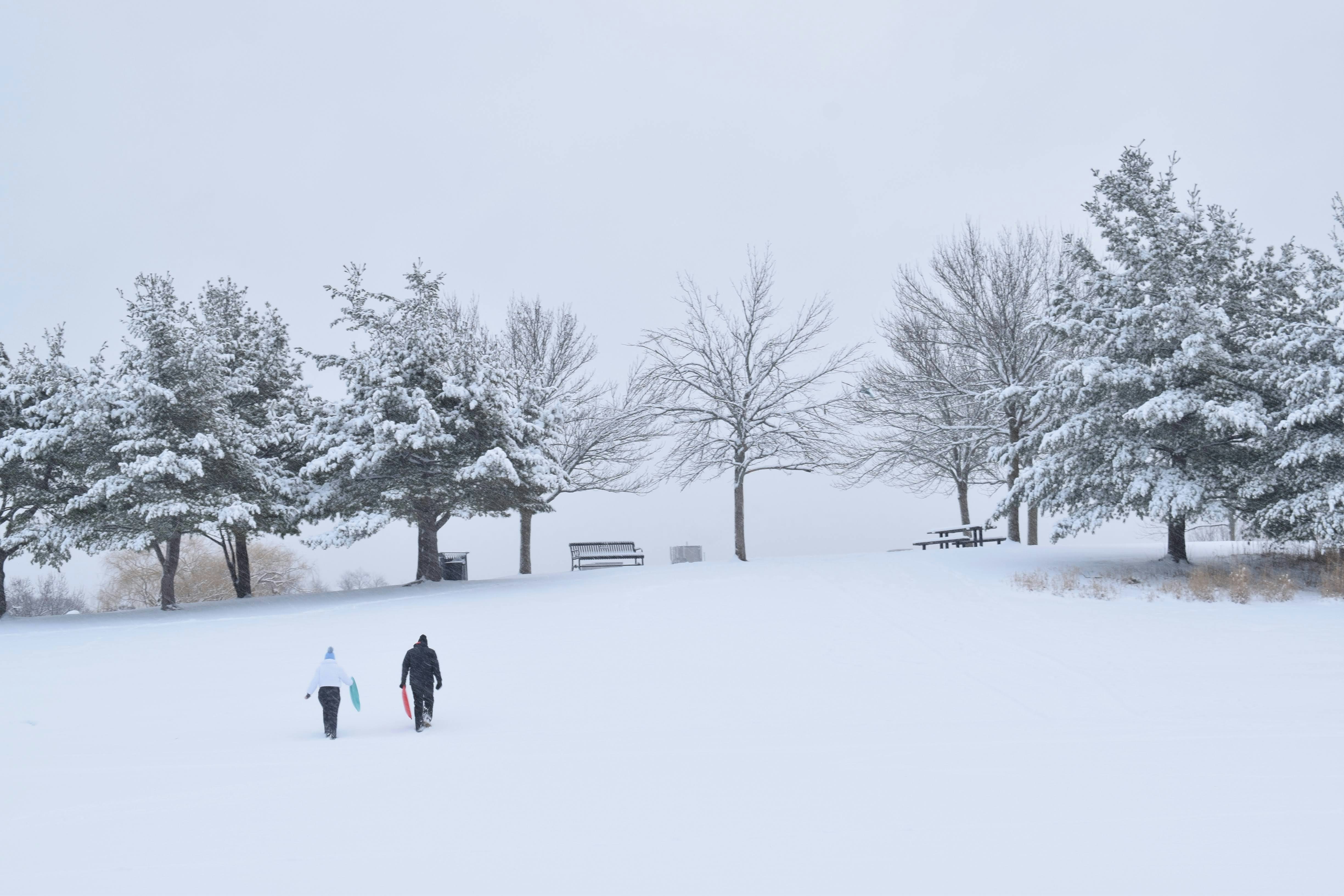 A couple of people walking across a snow covered field