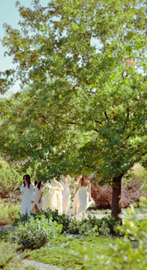 A group of women in white dresses standing under a tree