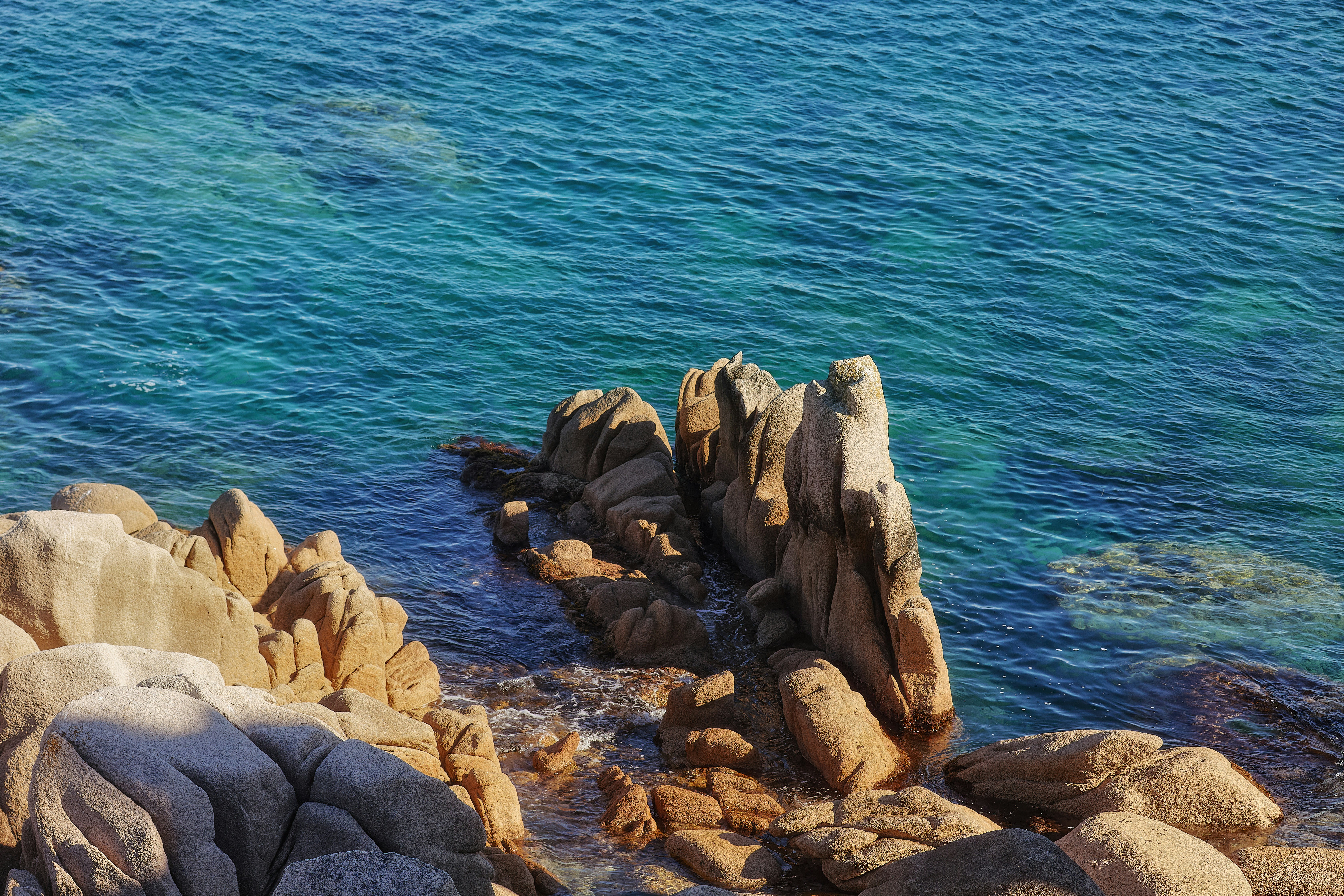 A rocky shore with blue water and rocks