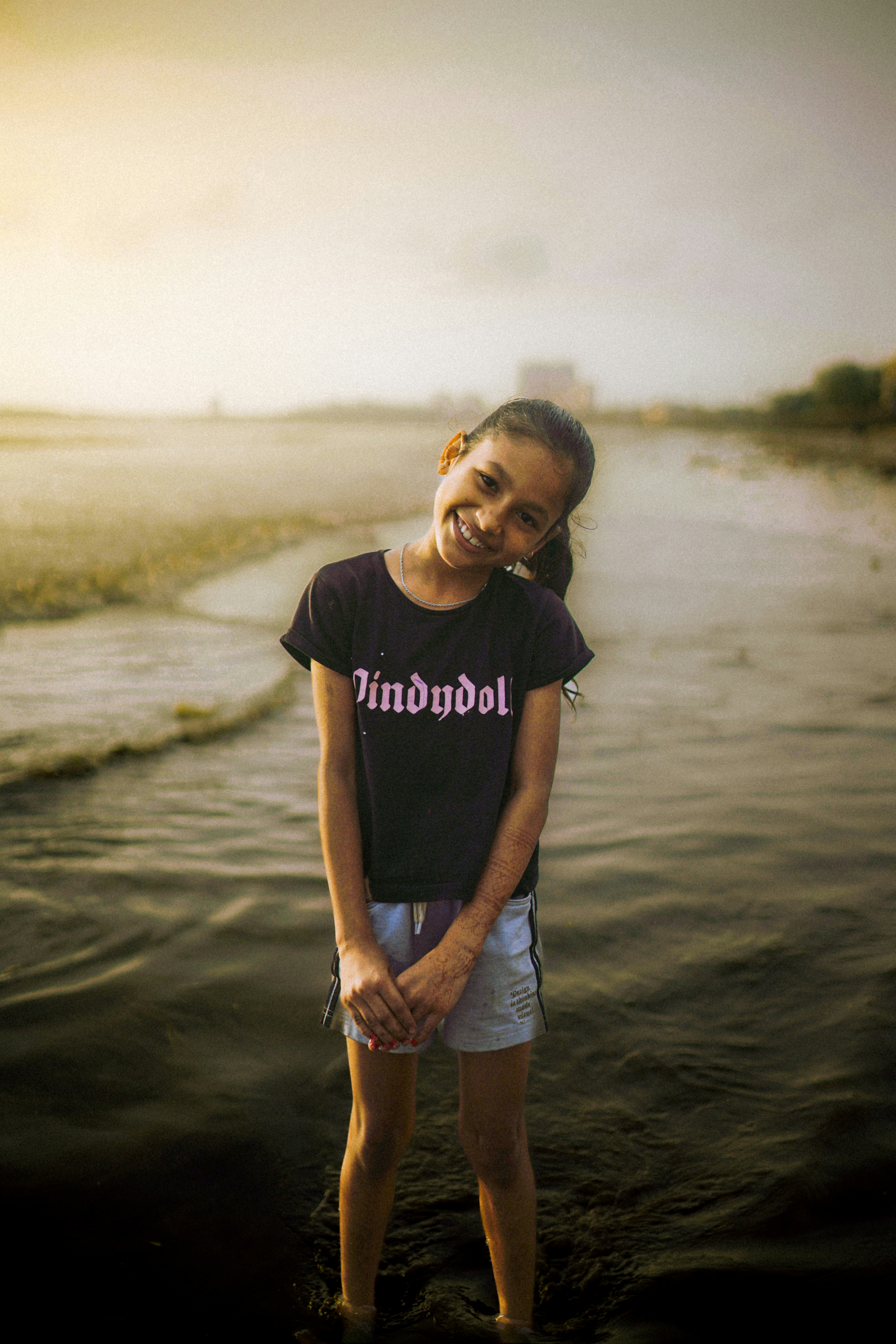 A young girl standing in the water on a beach
