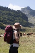 A person with a backpack standing in front of a herd of cows