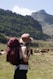 A person with a backpack standing in front of a herd of cows