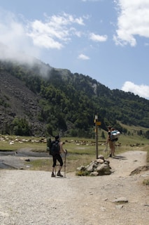 A couple of people walking down a dirt road