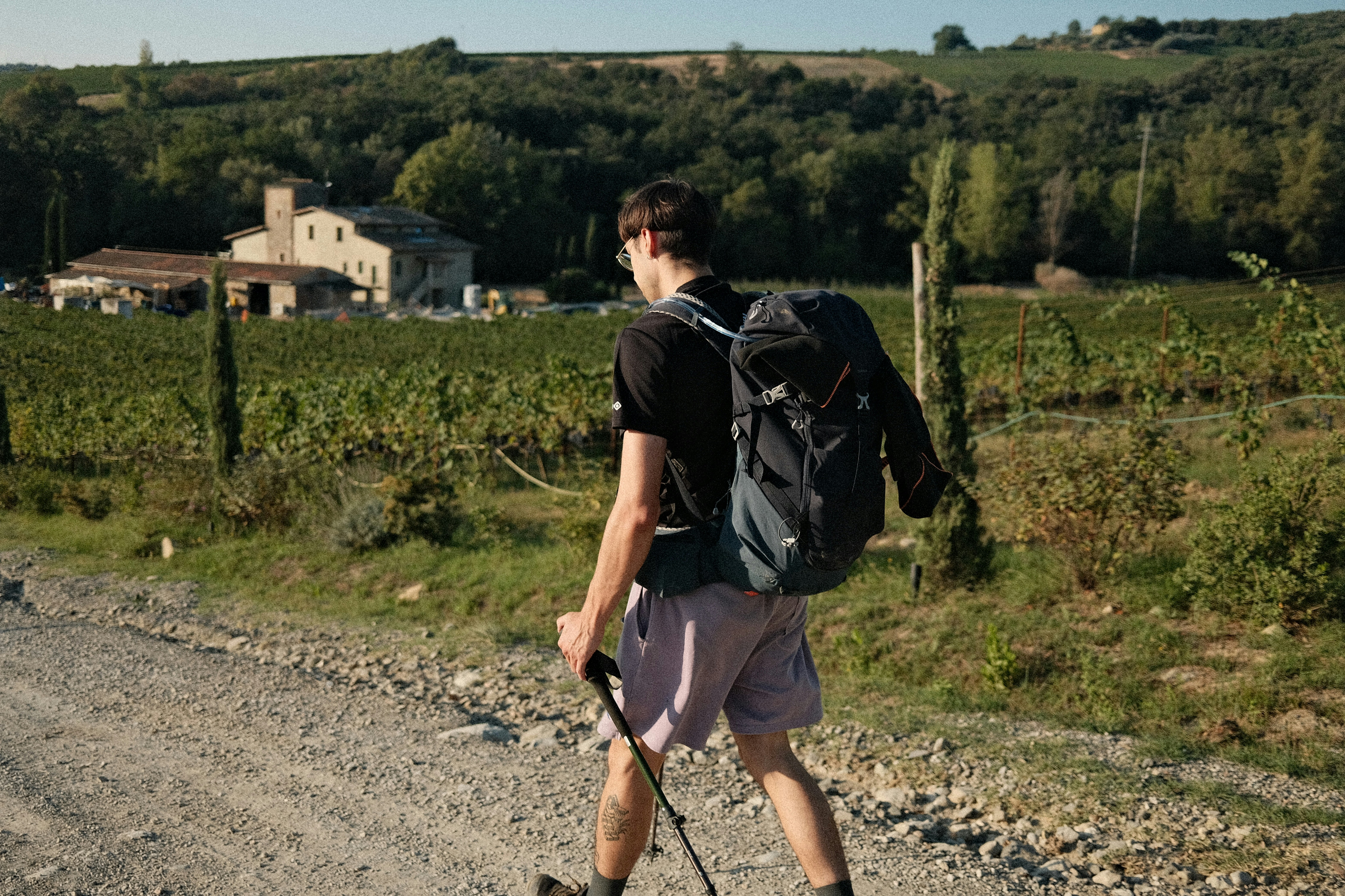 A man with a backpack walking down a dirt road