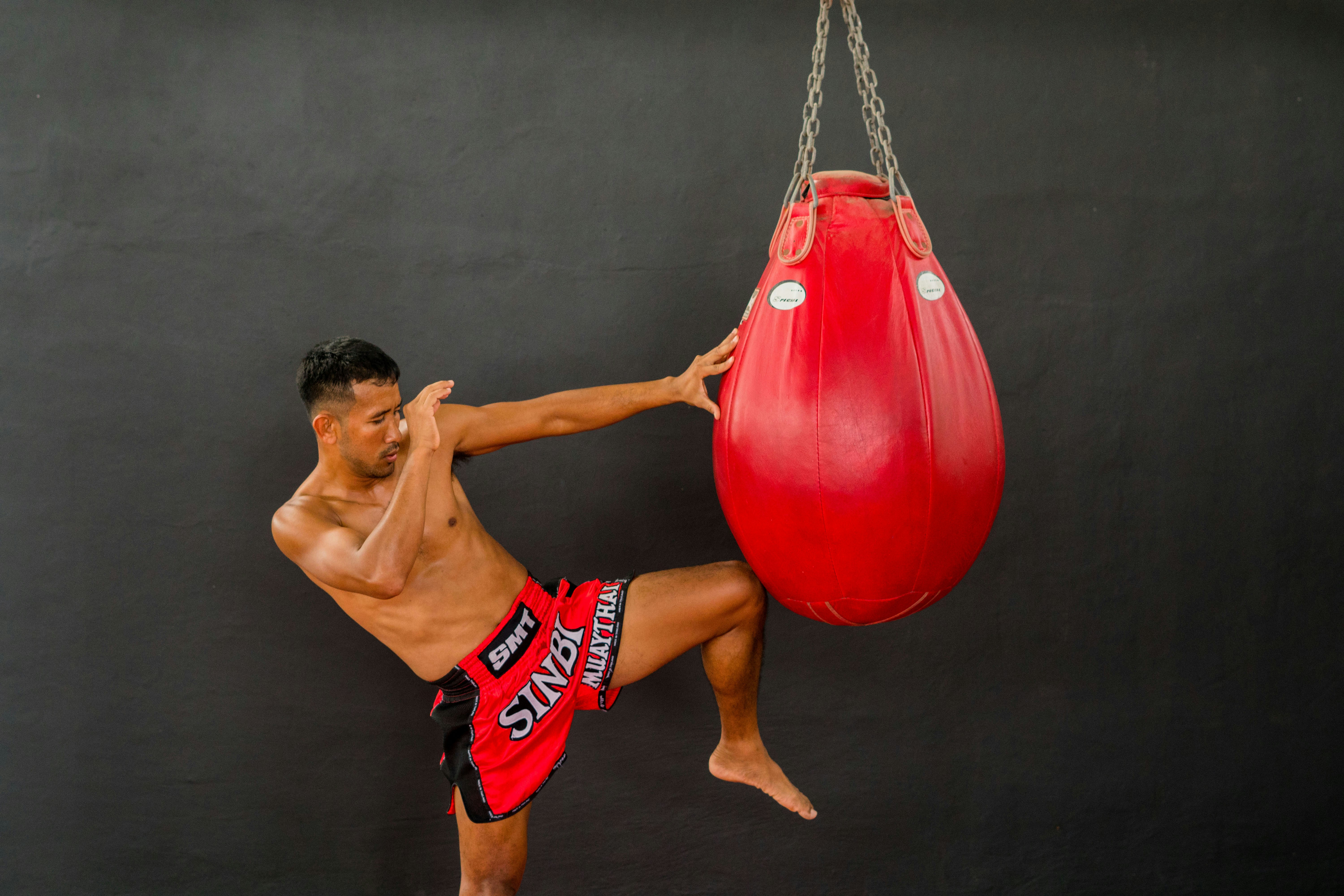 A man in red shorts and a red boxing bag