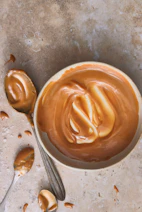 A bowl of peanut butter next to a spoon