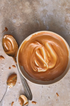 A bowl of peanut butter next to a spoon