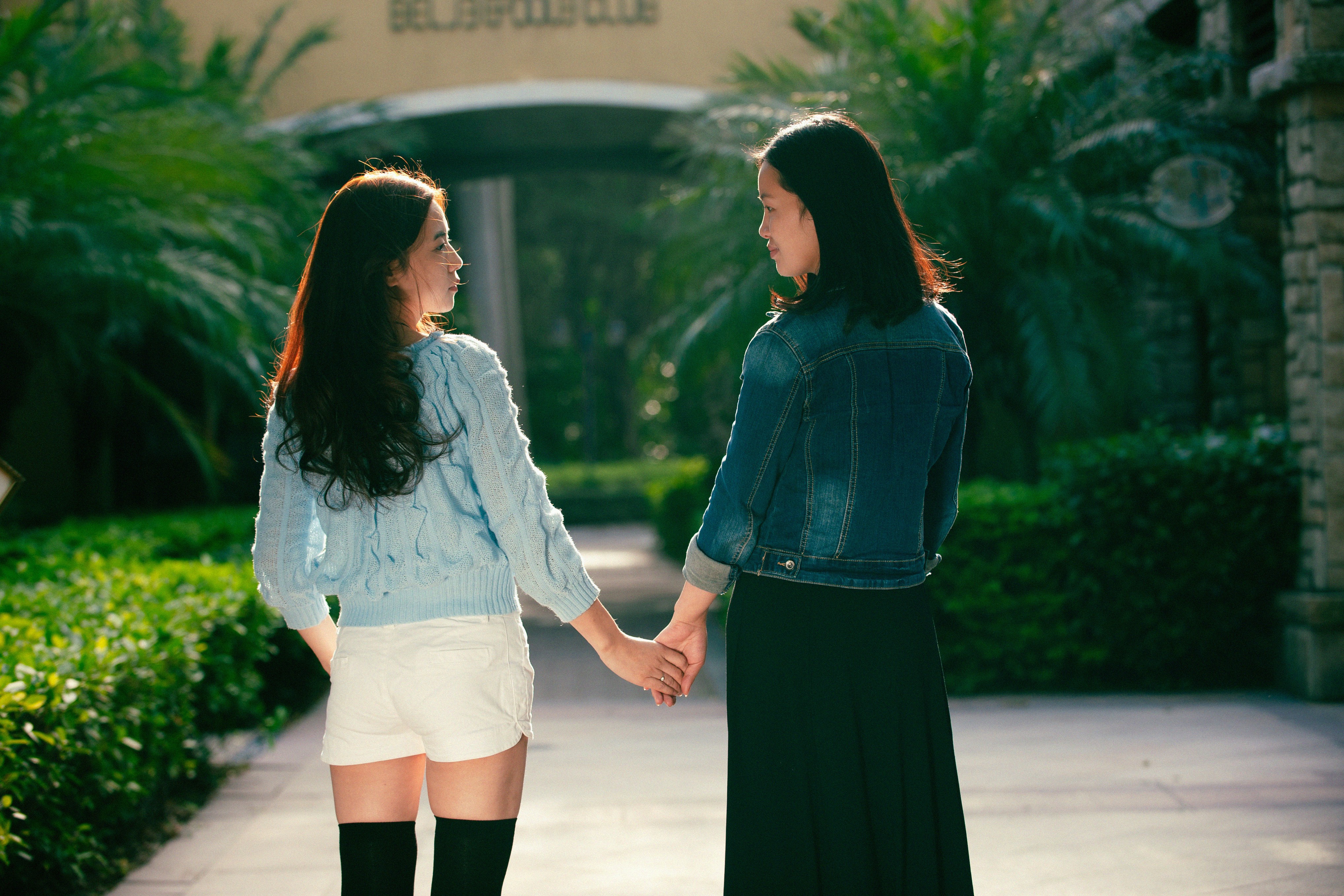 Two women holding hands walking down a sidewalk