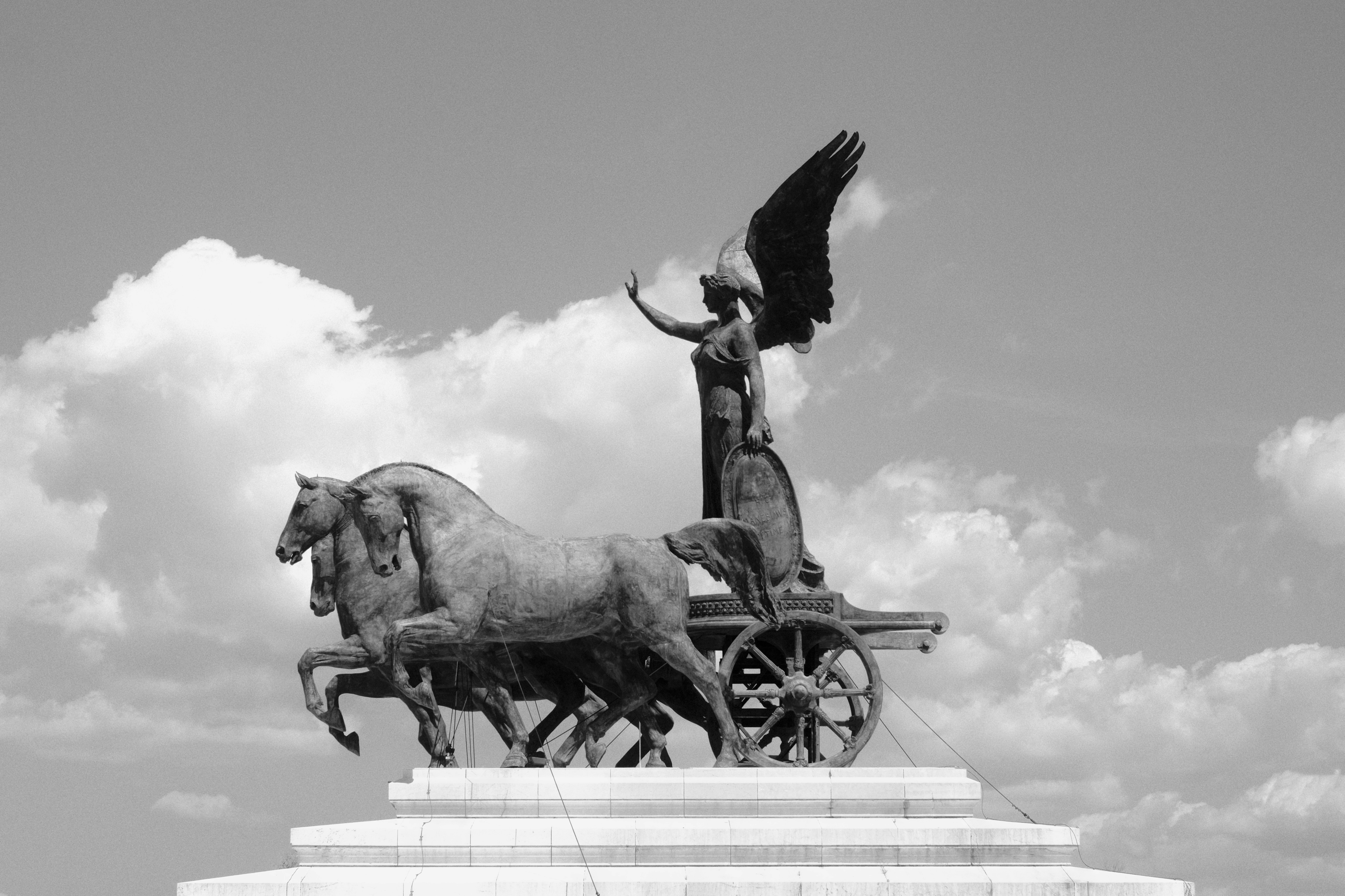 Uma foto em preto e branco de uma estátua de um cavalo e carruagem