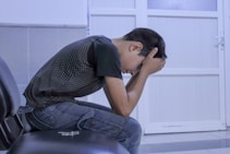 A man sitting on a chair with his head in his hands