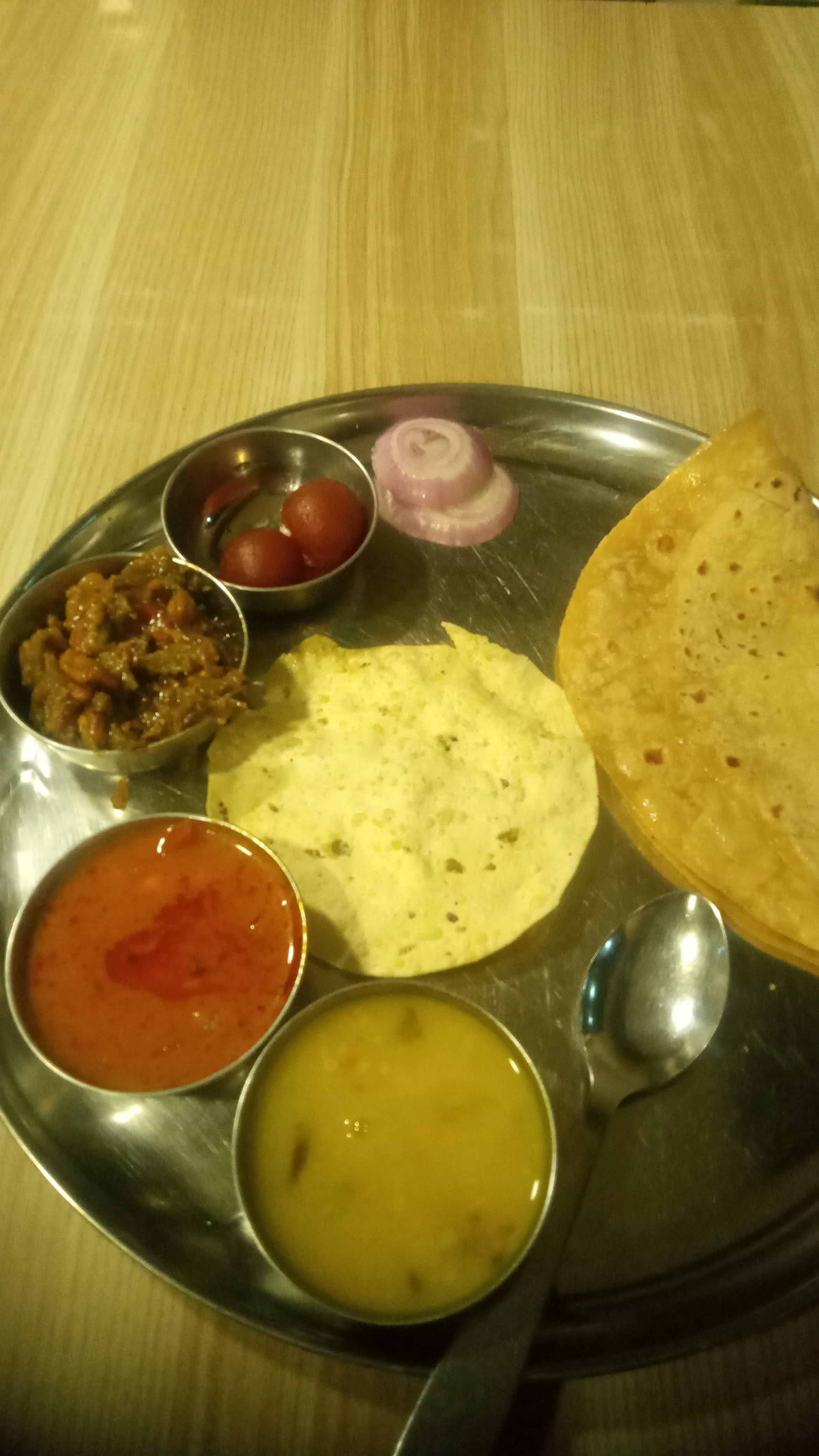 Festive Indian thali with puri, halwa, multiple vegetable curries and sweets arranged on a brass plate with marigold decoration