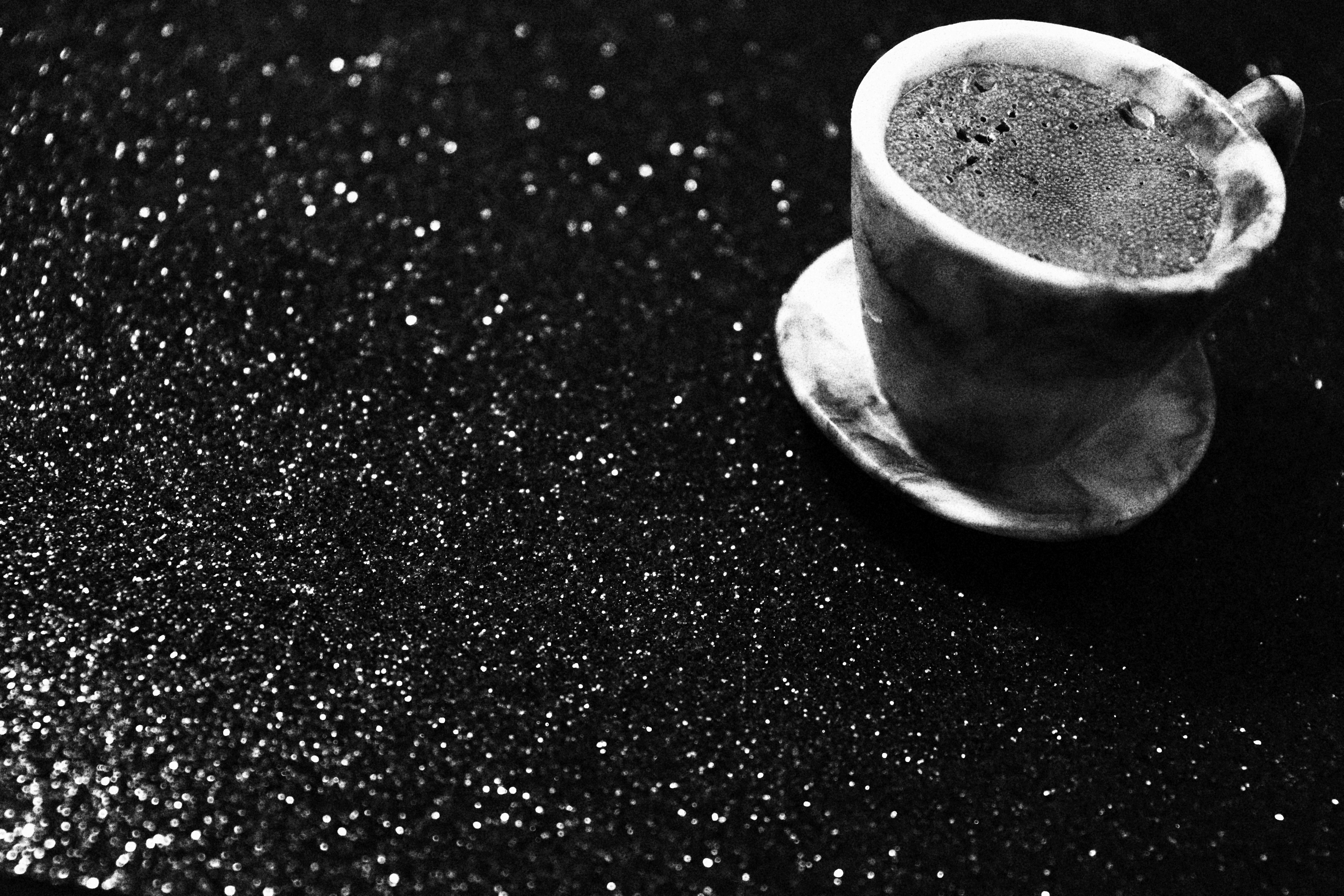 Dark coffee in a black matte cup, low key studio lighting, stark monochrome composition