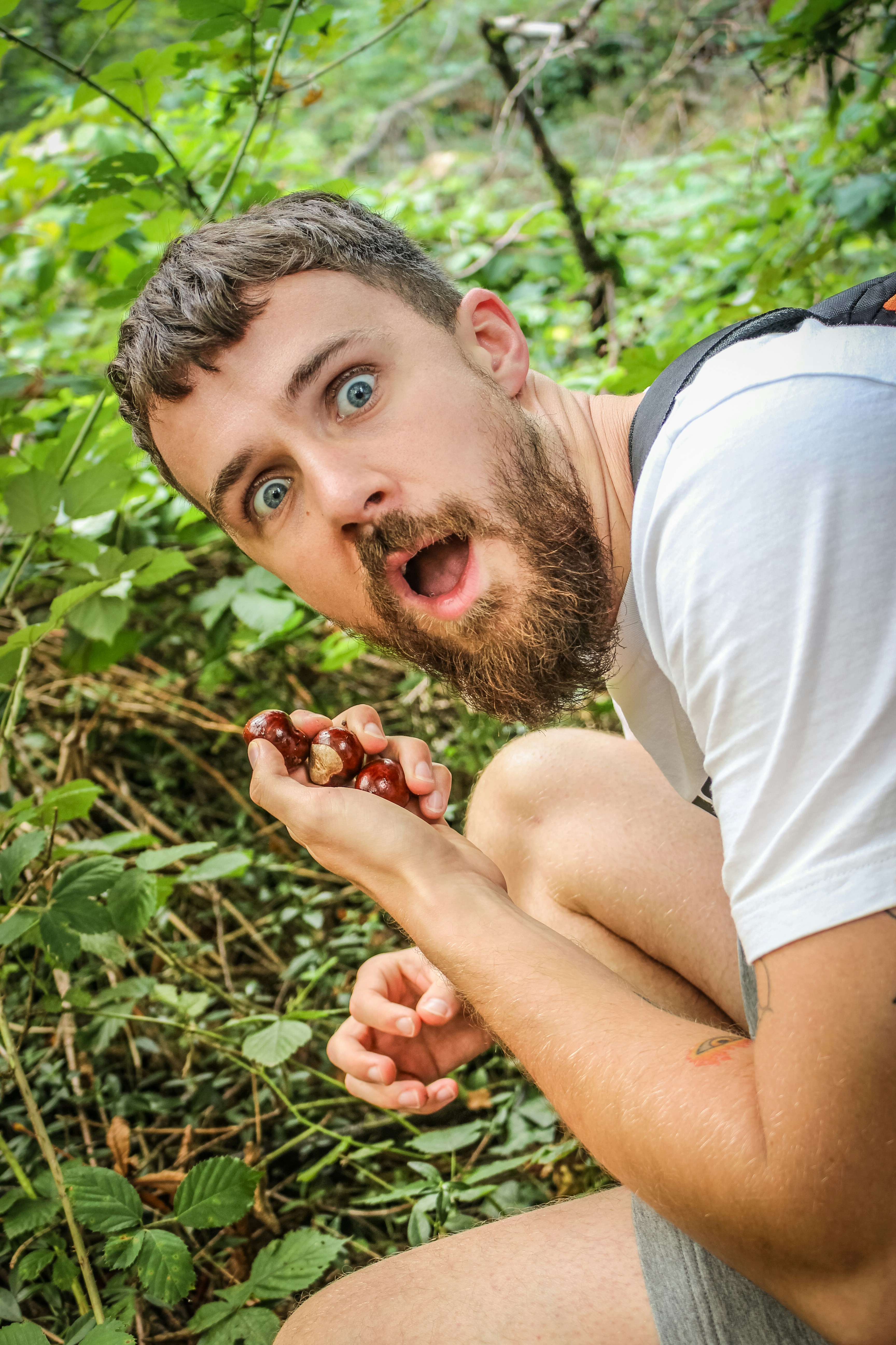 A man in a white shirt is eating a berry