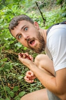 A man in a white shirt is eating a berry