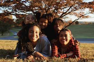 A group of young people laying on top of a grass covered field