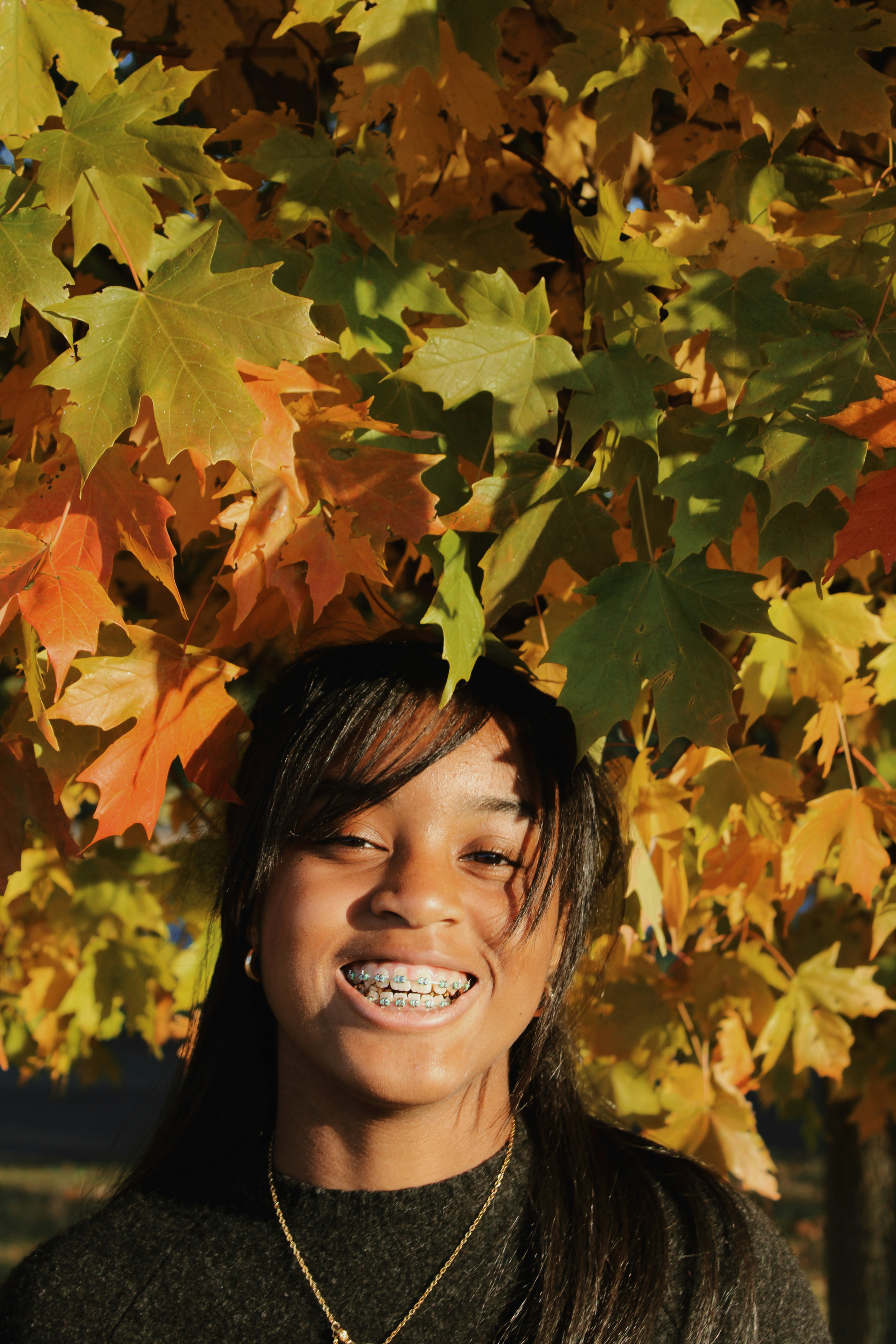 A woman standing in front of a tree with leaves on it photo – Free ...