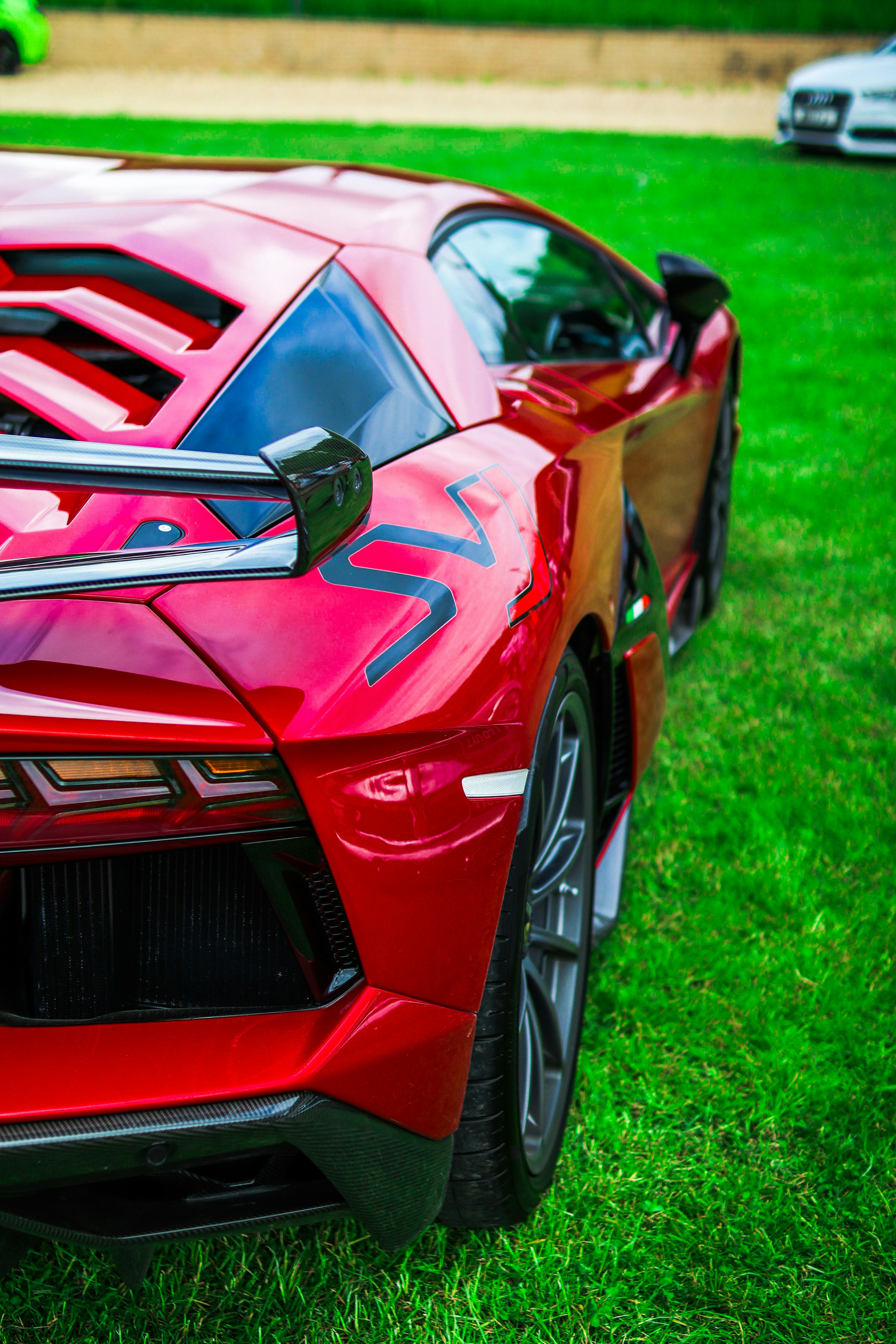 A red sports car parked on top of a lush green field