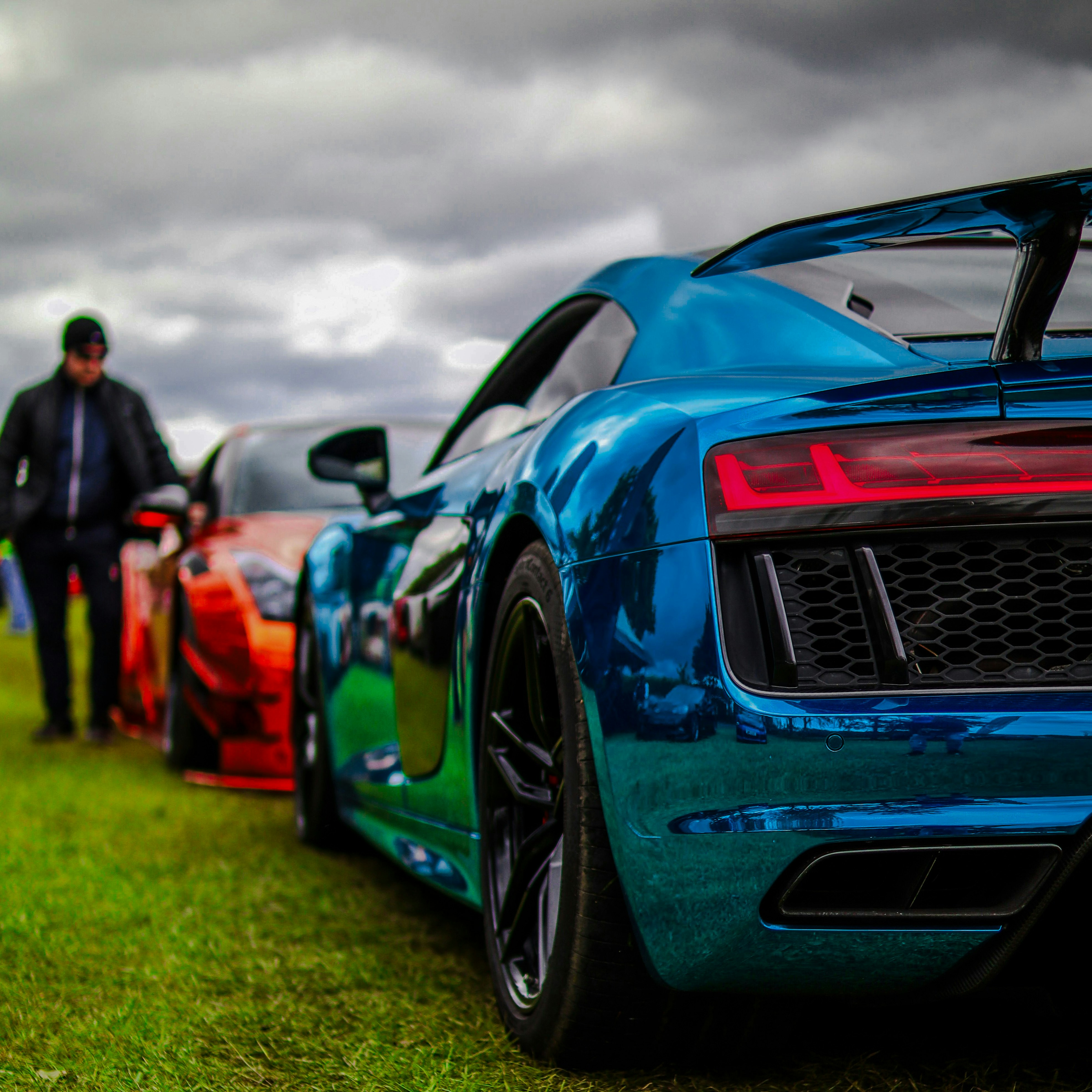 A man standing next to a blue sports car