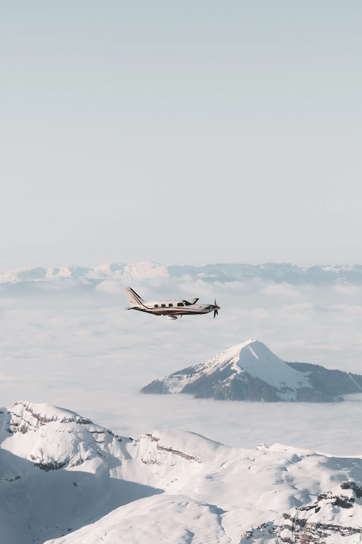 A passenger aircraft seen from above as it flies over a range of snow-covered mountains