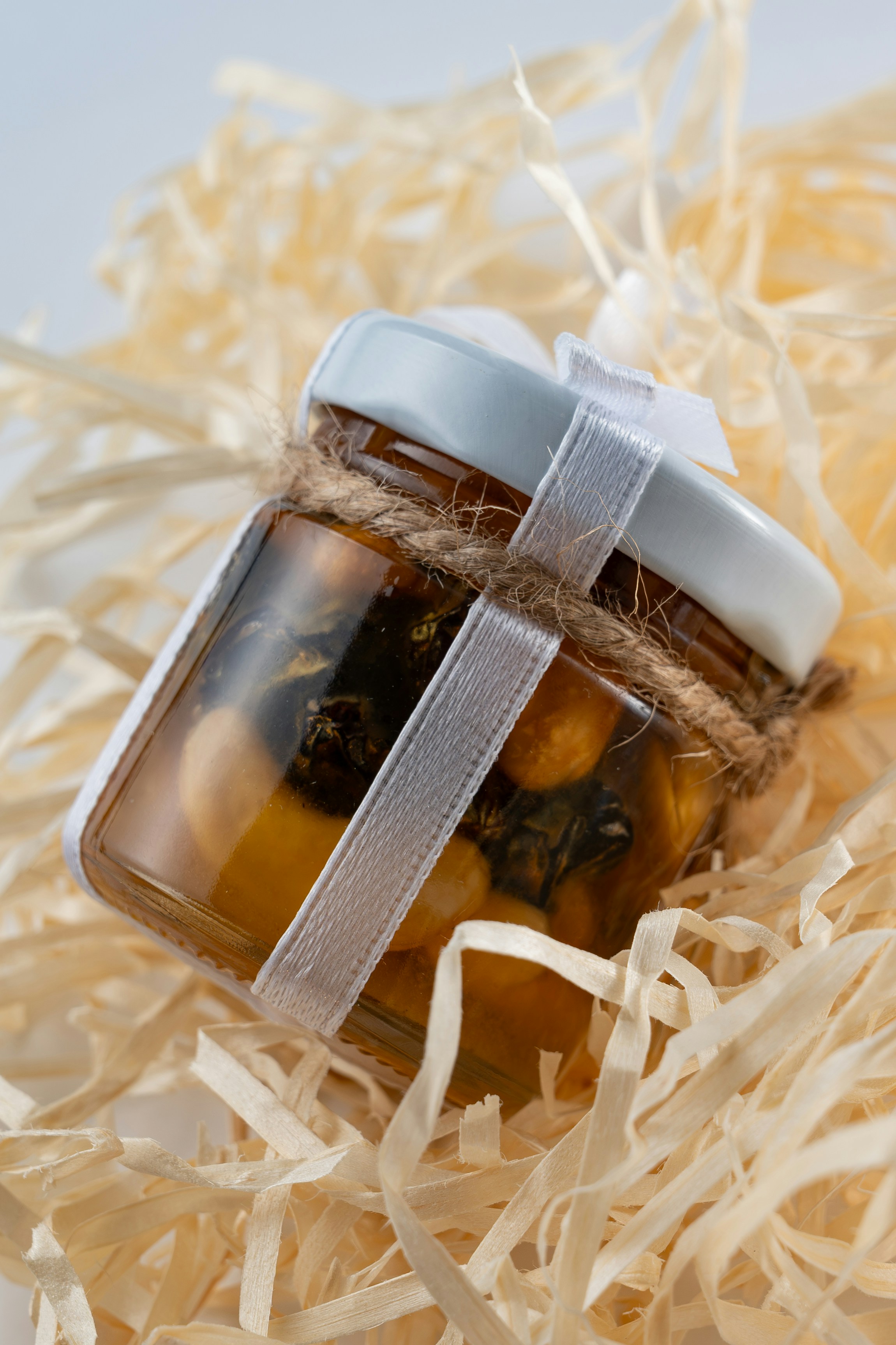 A jar of honey sitting on top of a pile of shredded paper